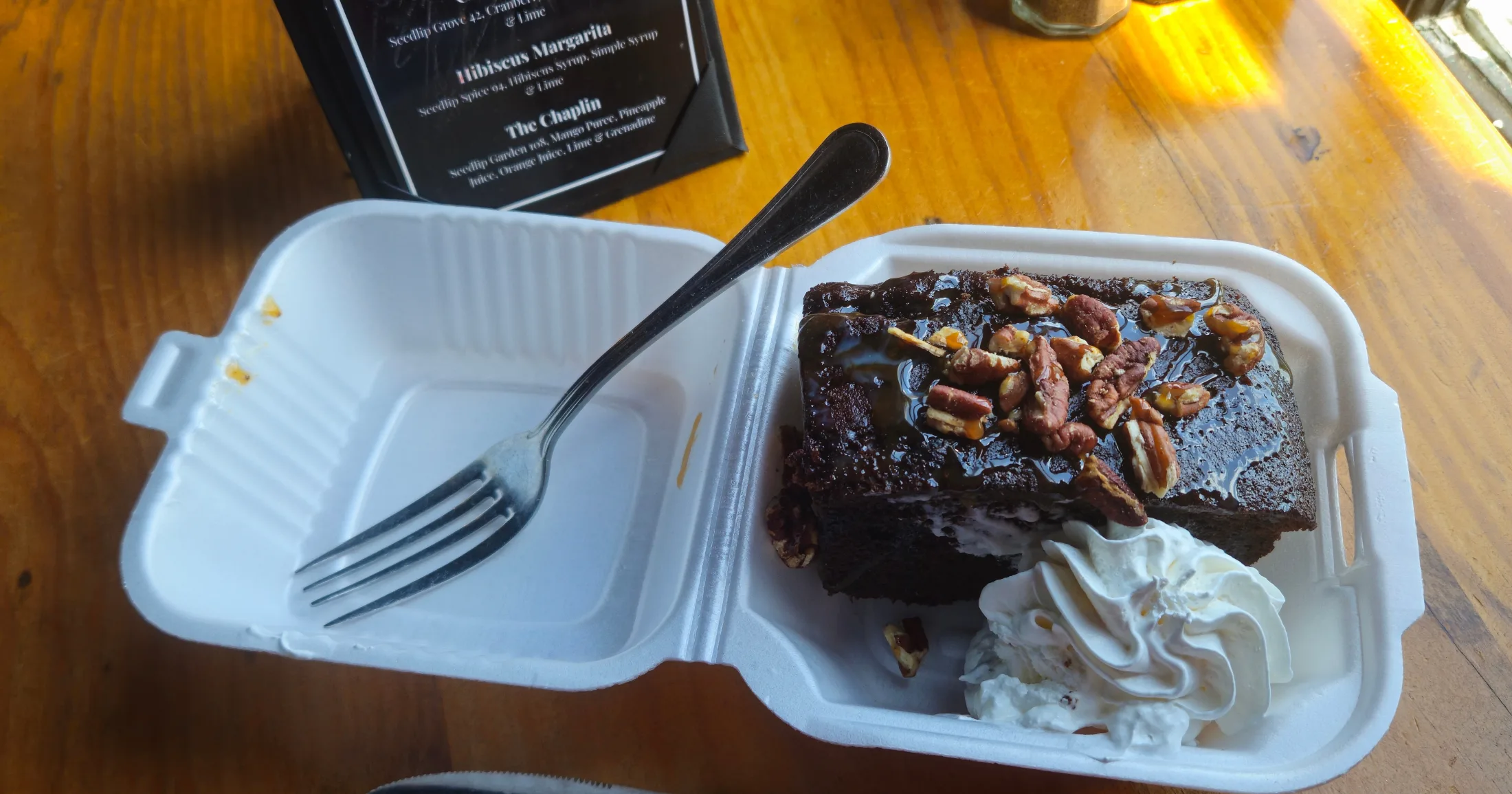 Wunsche Bros. whiskey cake with pecan glaze and whipped cream in a takeout container