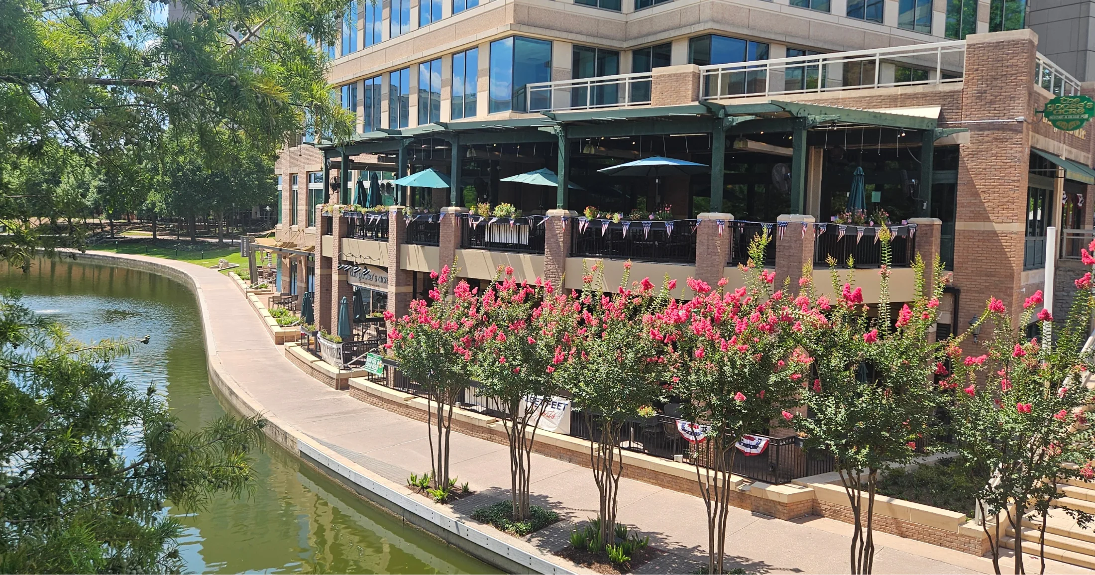 Waterway-front restaurant patios with blooming crape myrtles along the canal
