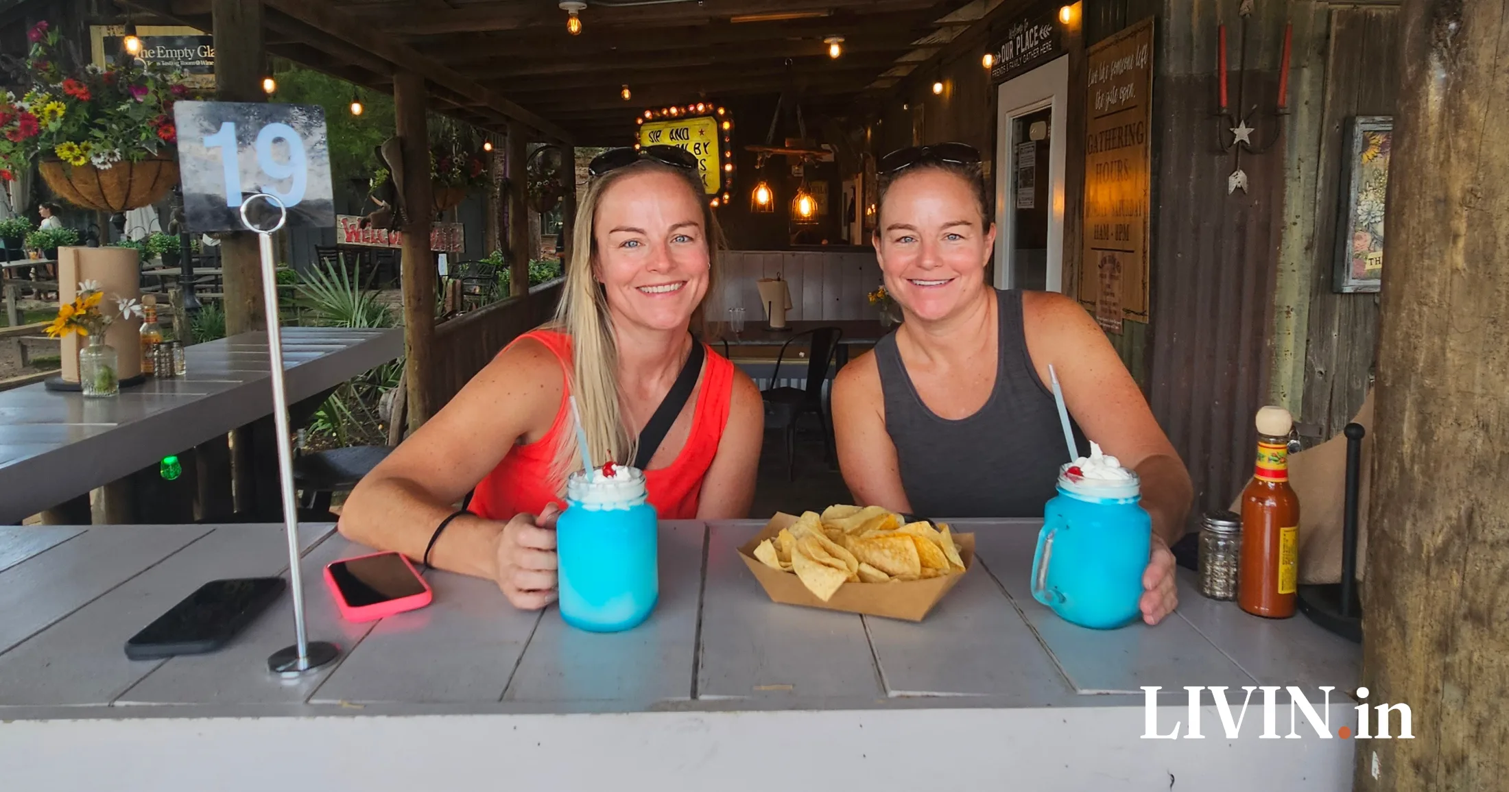 Wendy and Kelly enjoying blue curacao margaritas in mason jars on the covered patio at Hee Haw's Tacos and Tequila in Old Town Tomball