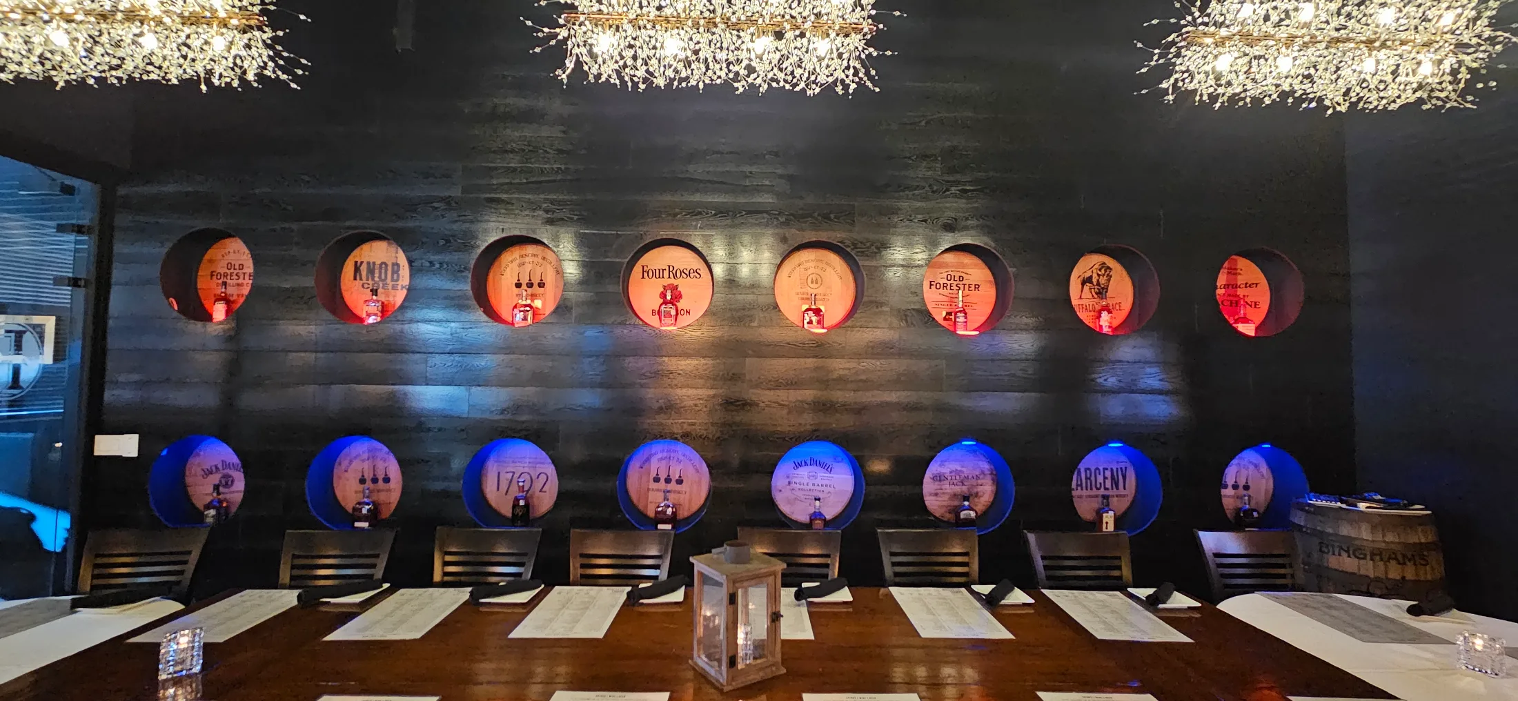 Private dining room at Federal American Grill with whiskey barrels mounted on a dark wood wall, lit in red and blue