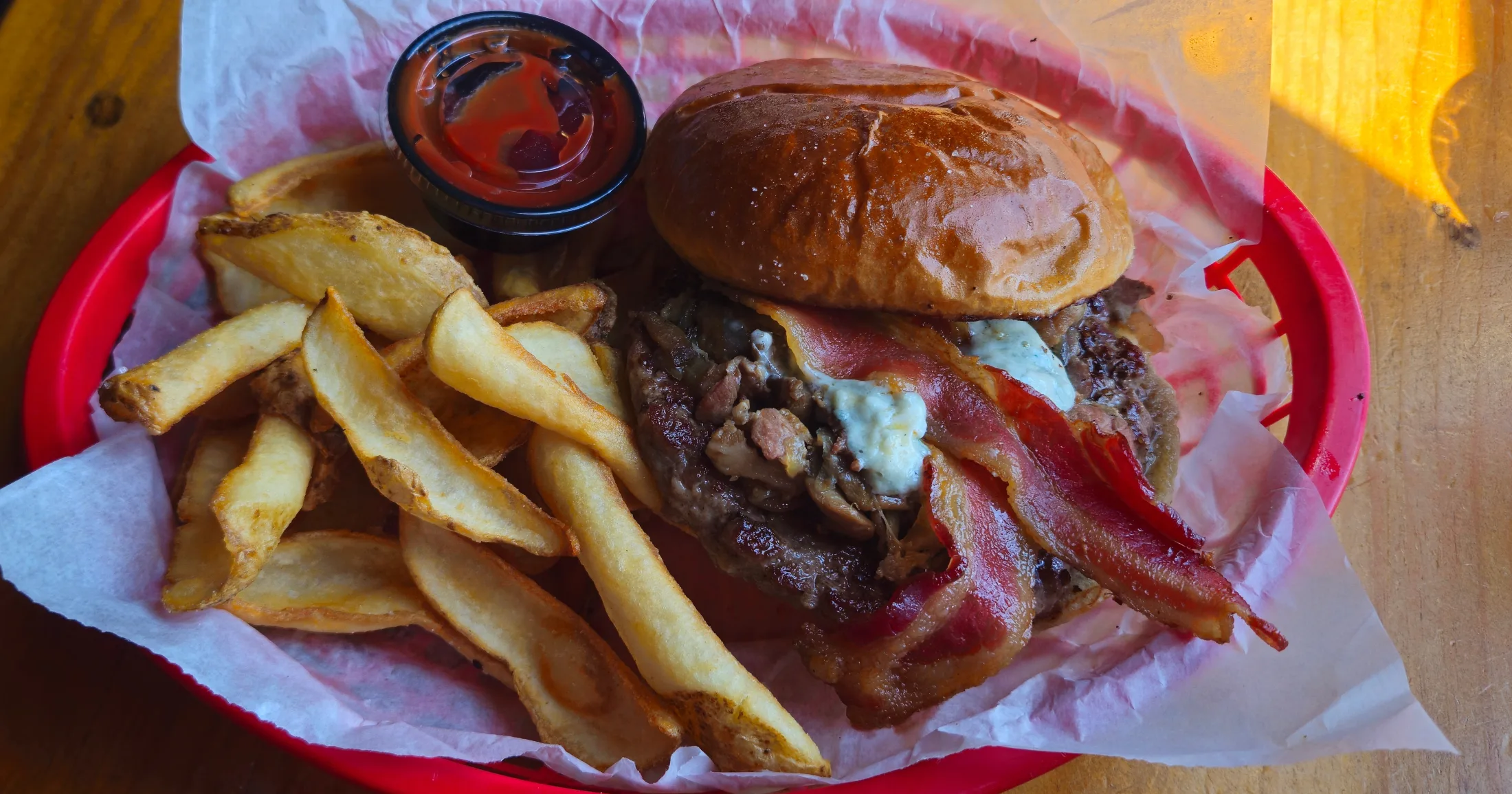 Blue cheese burger with bacon and hand-cut fries in a red plastic basket