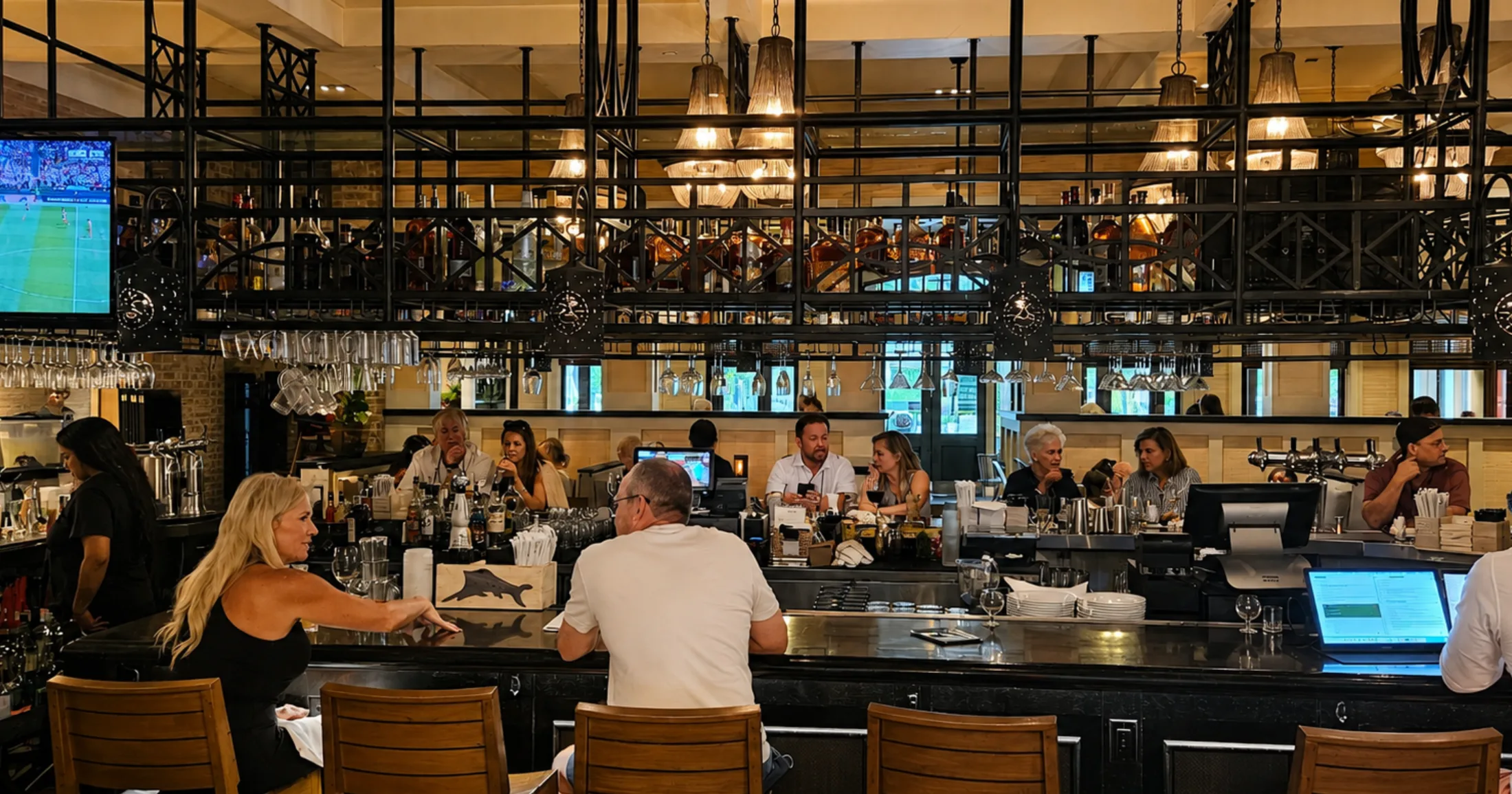 The Bar at Tommy Bahama Market Street, full of guests with copper fixtures and warm lighting