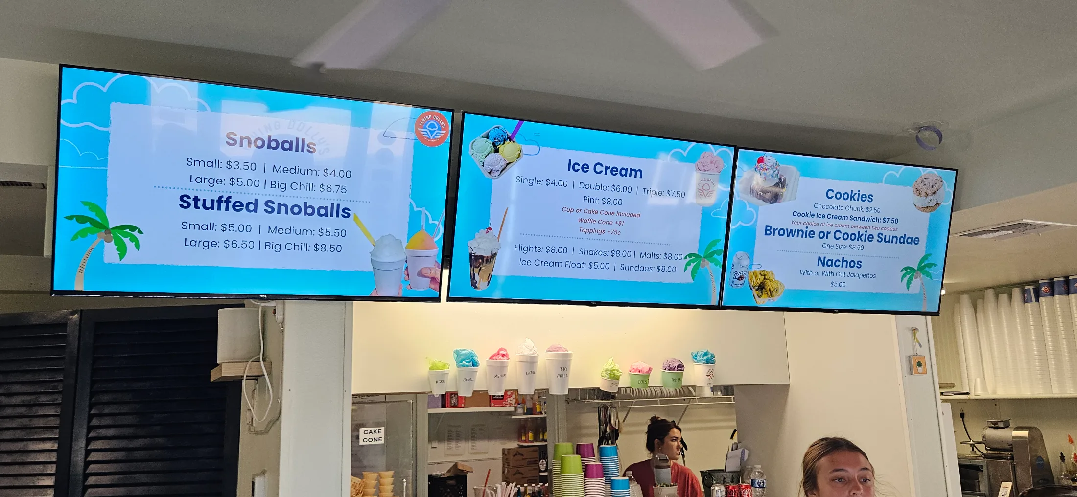 Flying Dolly's digital menu boards showing full pricing for snoballs, stuffed snoballs, ice cream, cookies, and nachos