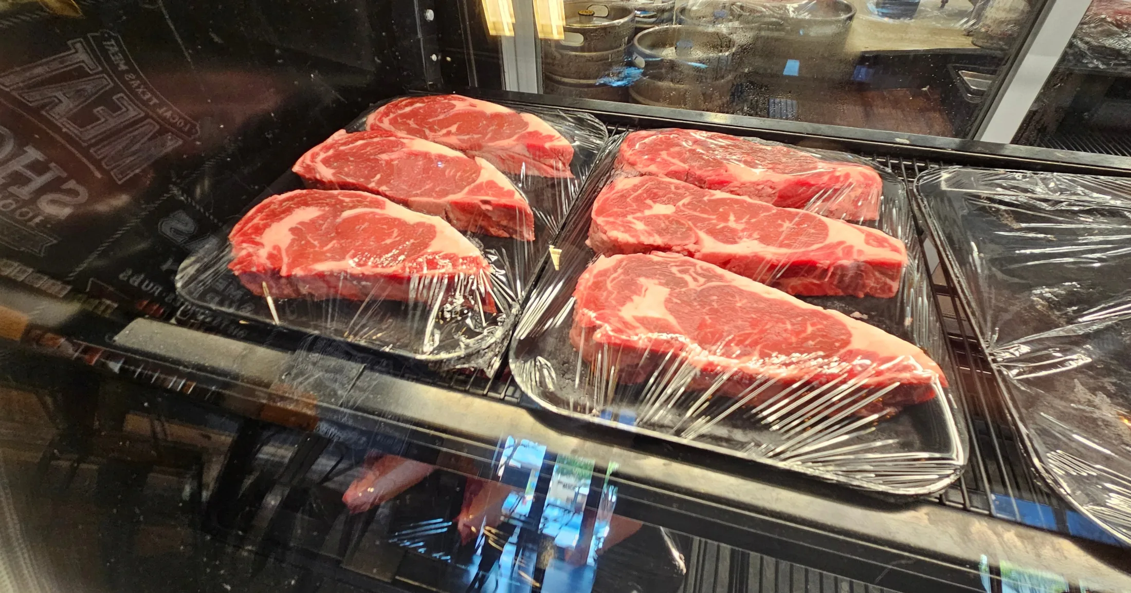 Fresh ribeye steaks displayed in the Tejas Meat Supply butcher case