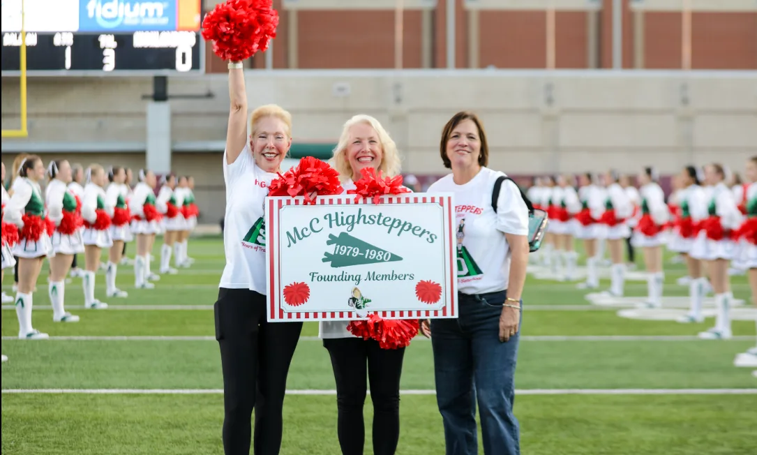 Three Founders hold a McC Highsteppers 1979-1980 Founding Members sign on the field at Woodforest Bank Stadium