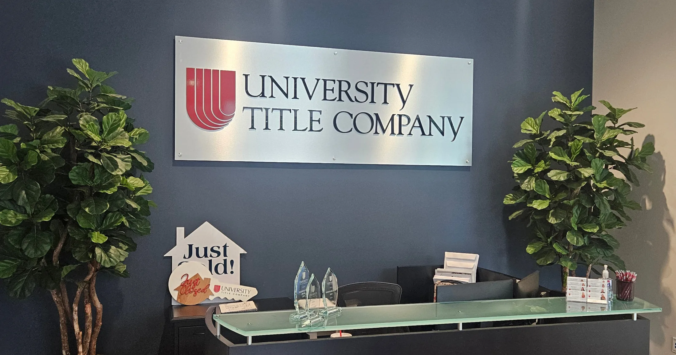 University Title Company reception desk with Just Sold sign and crystal awards