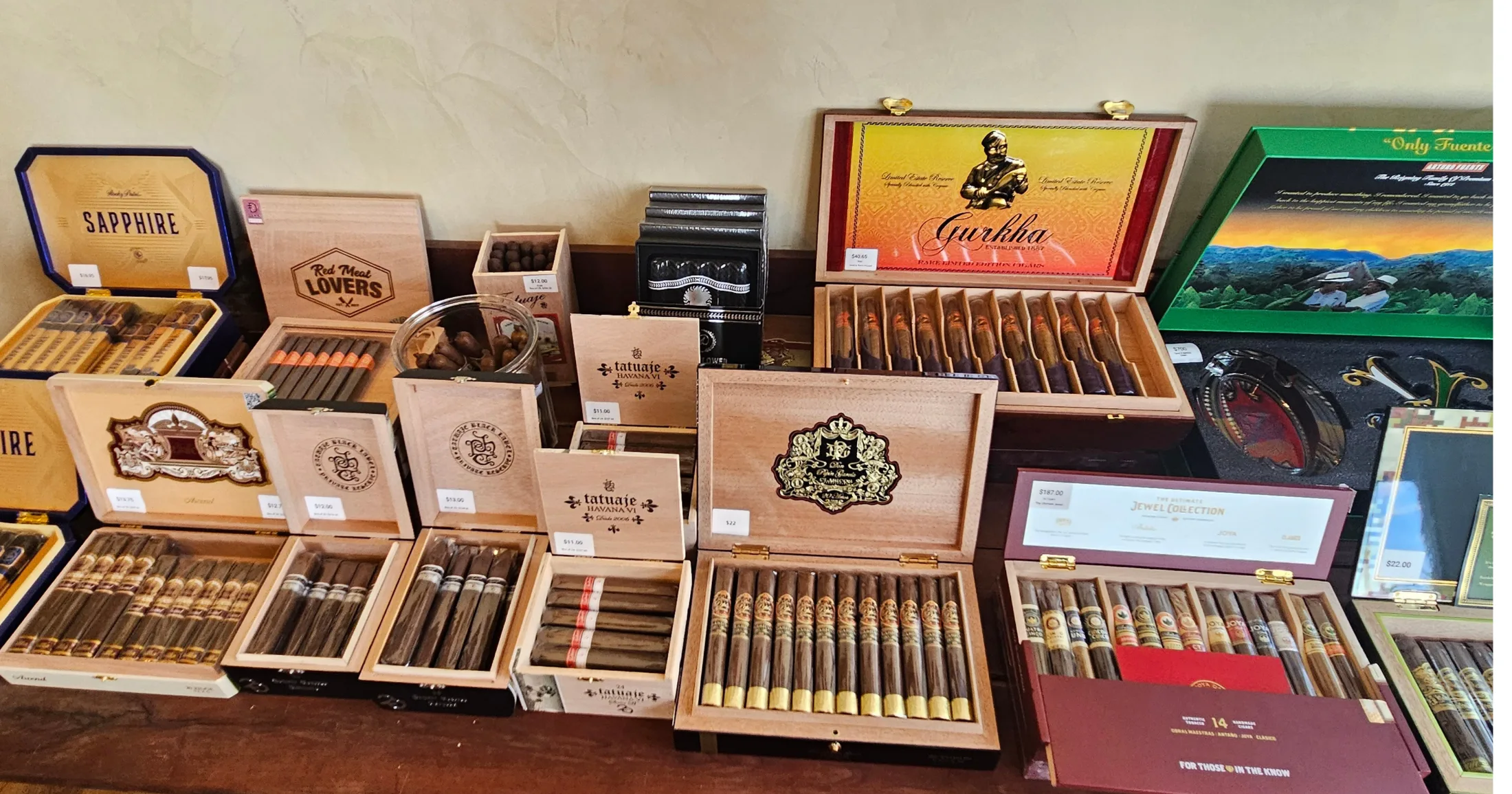 Open cigar display cases showing Tatuaje, Gurkha, Oliva, and other premium brands with visible price tags