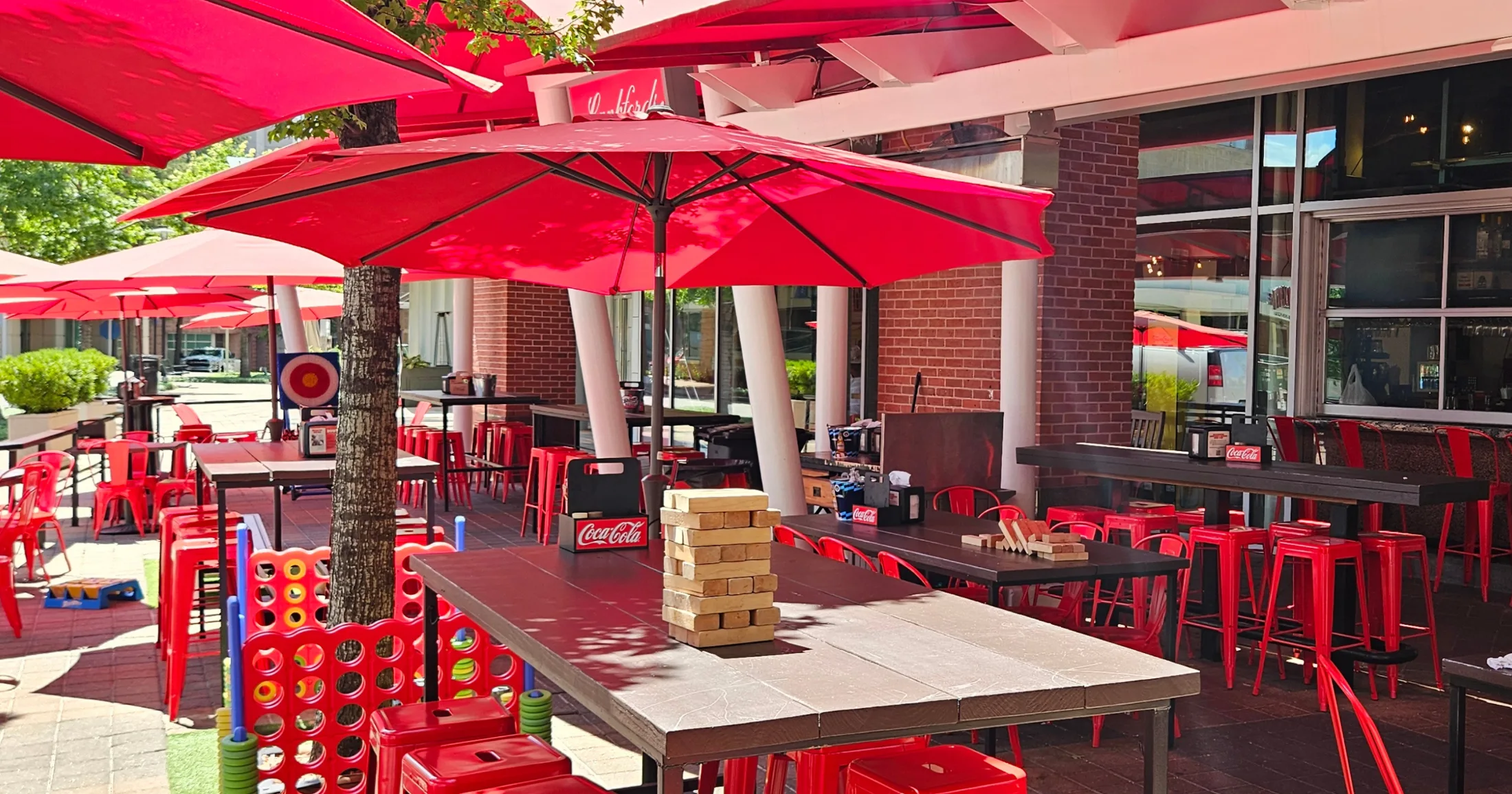 Covered patio with red umbrellas, giant Jenga, and Connect Four games set up for guests