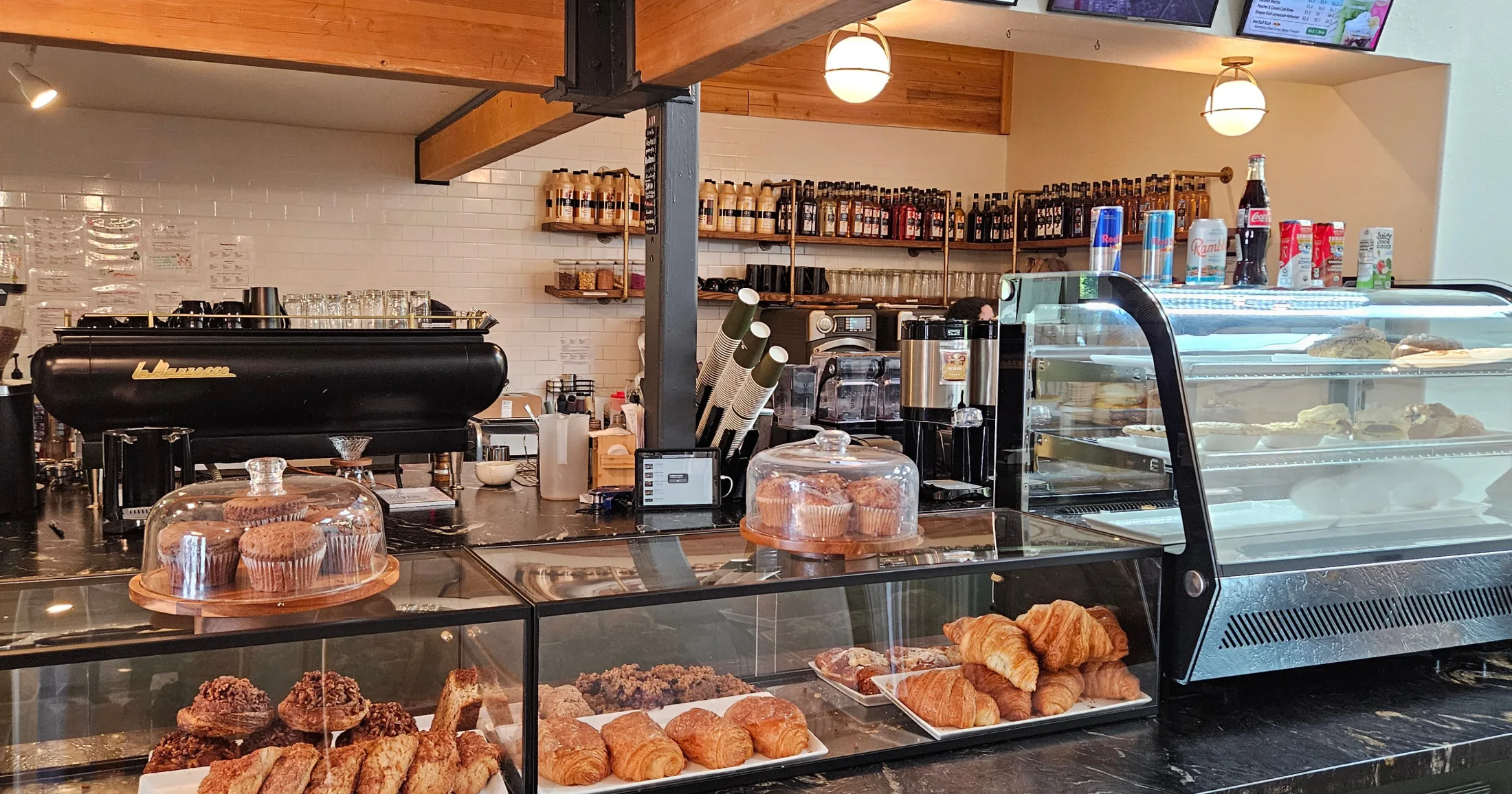 First Cup Coffee Co. espresso bar and bakery counter showing croissants, muffins, and pastries under glass