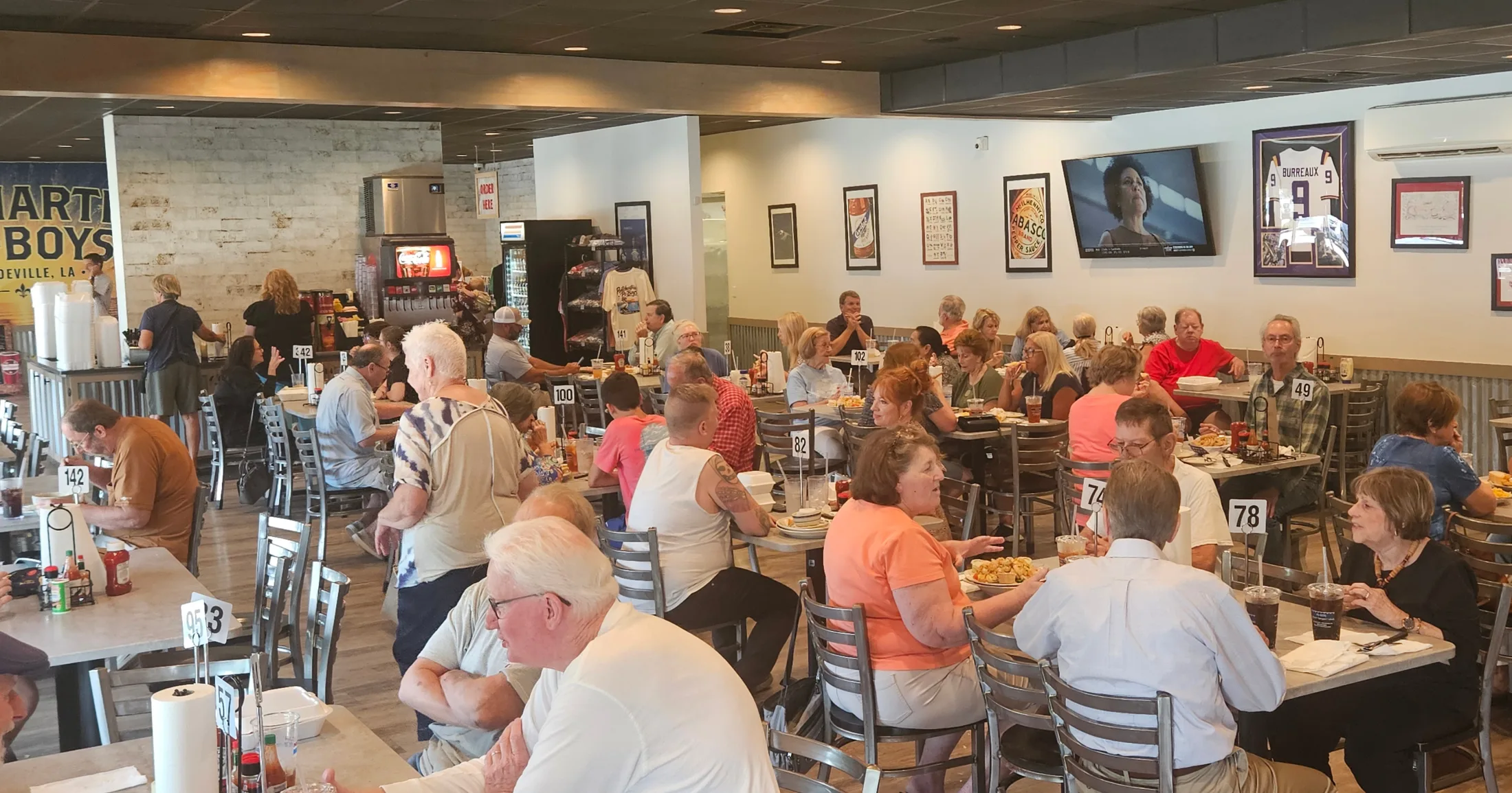 Packed dining room at Pontchartrain Po-Boys on a Wednesday afternoon, framed LSU and Saints memorabilia on the walls
