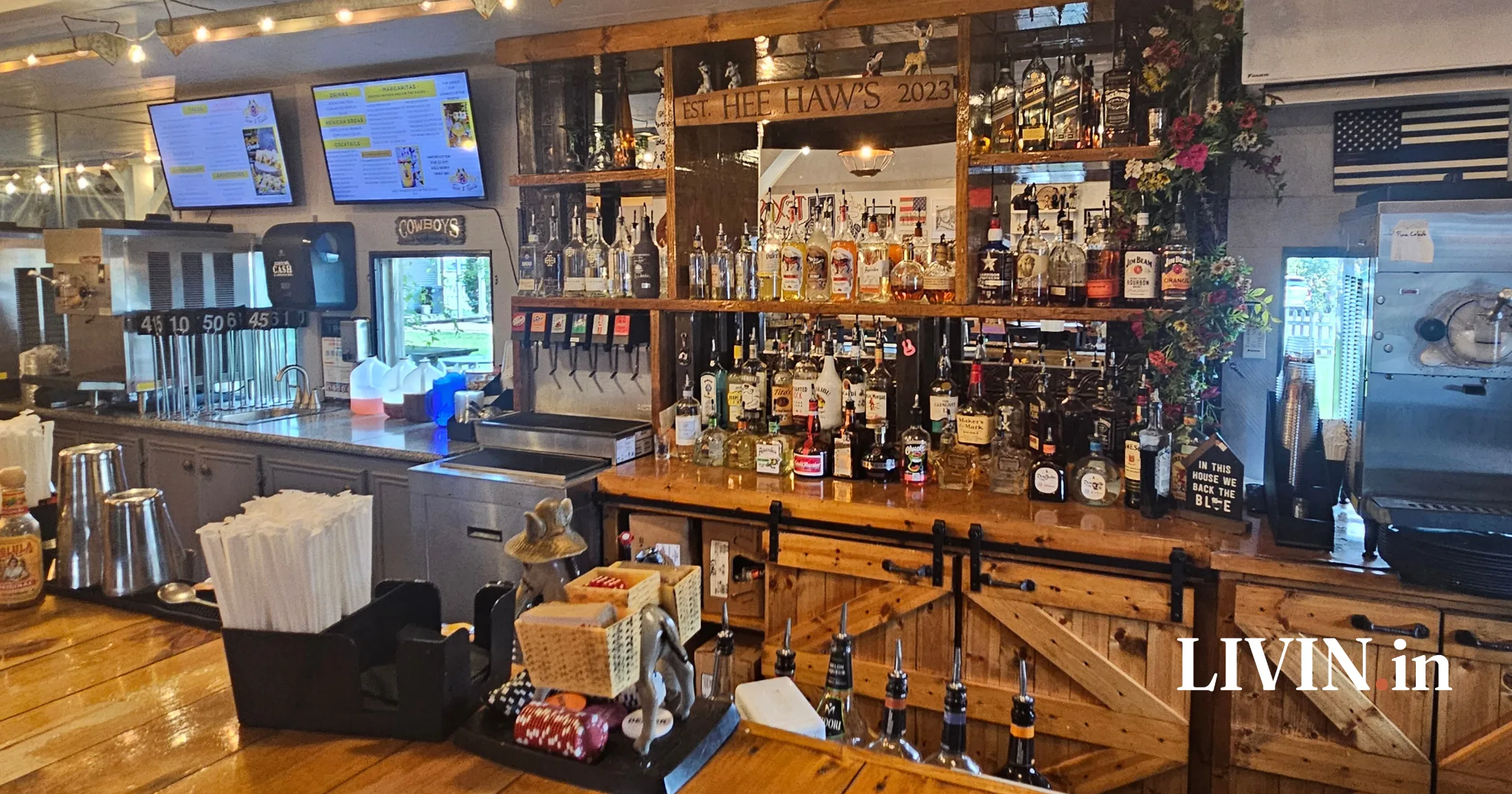Smiling bartender giving a thumbs up behind the bar at Hee Haw's Tacos and Tequila with the full menu board visible