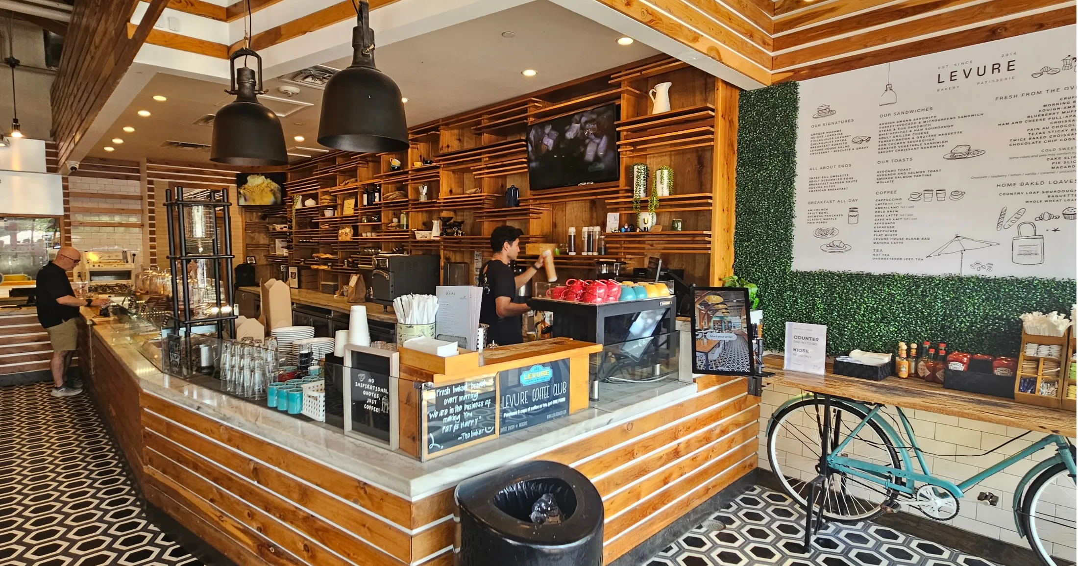 Levure Bakery and Patisserie interior with wood counter, hexagon tile floor, and barista at work
