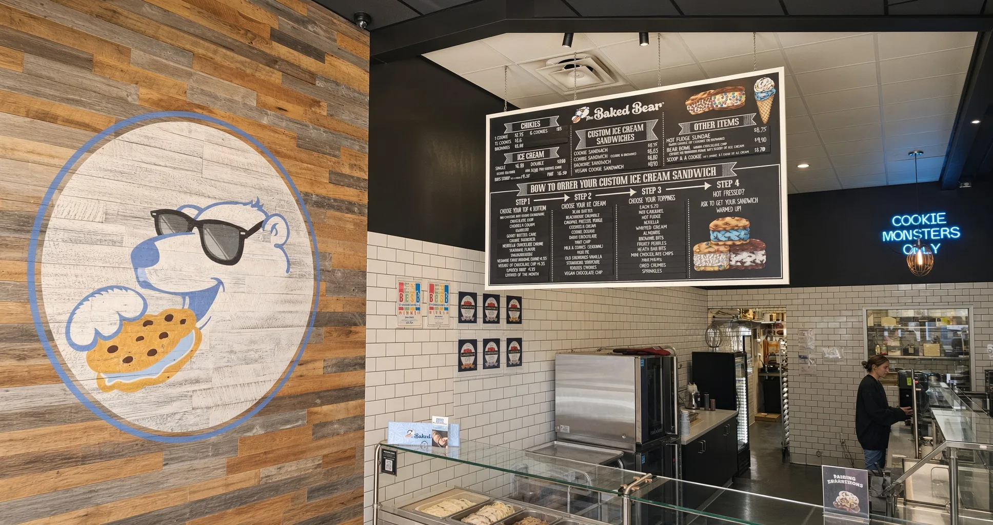 Interior of The Baked Bear in Georgetown showing the chalkboard menu and signature bear logo on reclaimed wood wall