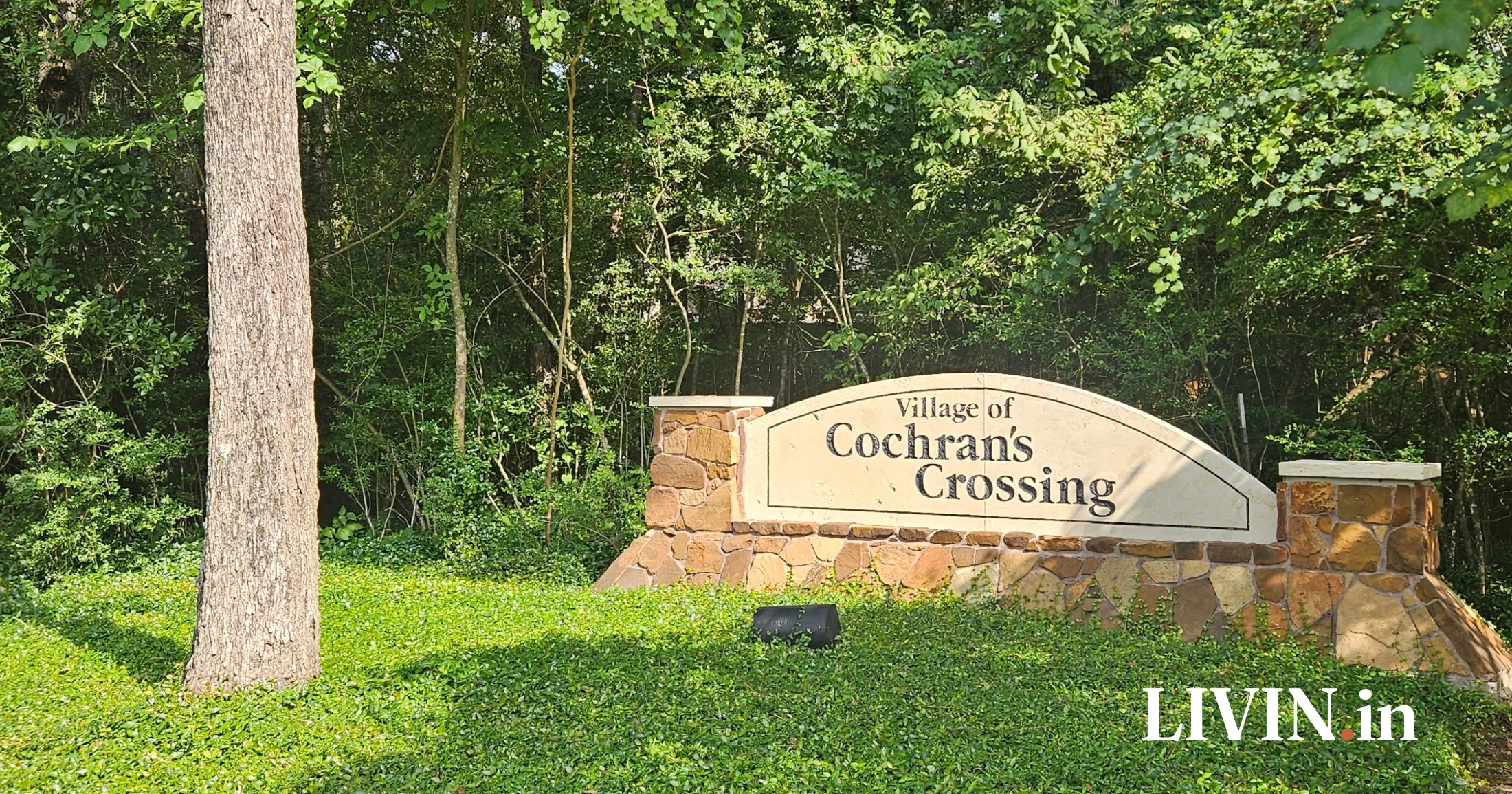 Village of Cochran's Crossing stone entrance sign surrounded by dense tree canopy, The Woodlands, Texas
