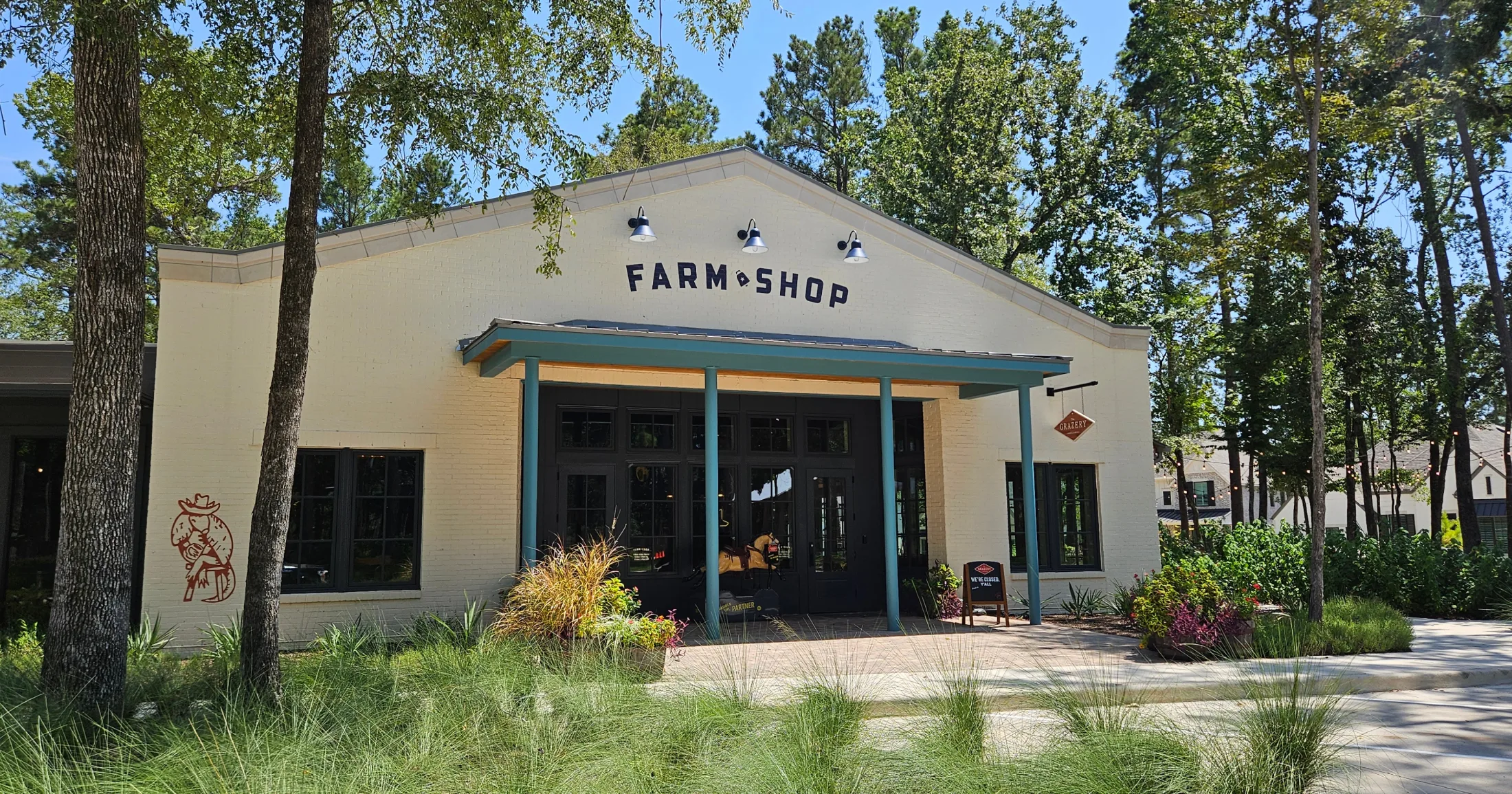Farm Shop building with cream brick exterior and teal columns surrounded by landscaping
