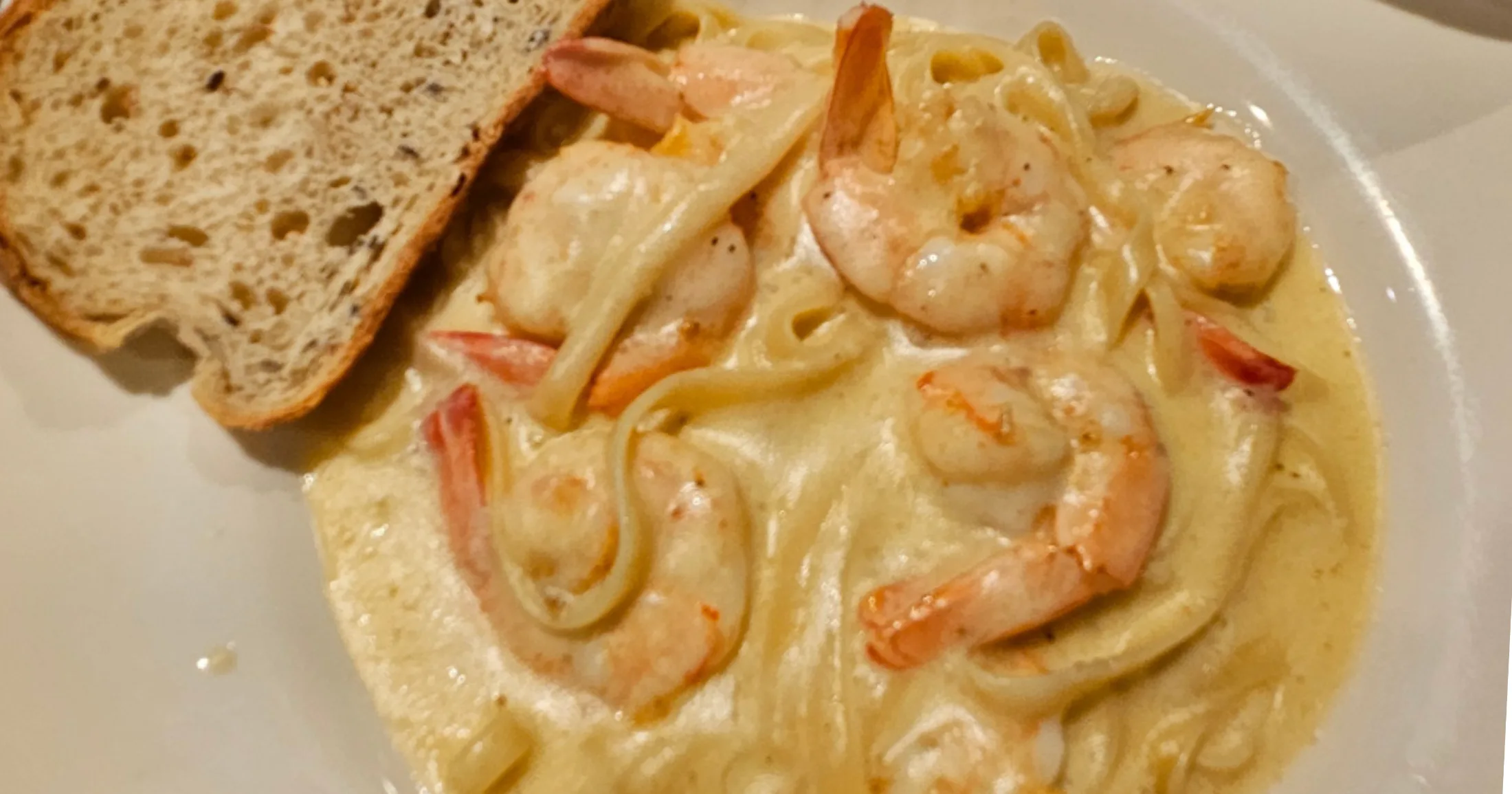 Shrimp pasta in a creamy sauce with toasted bread, close up