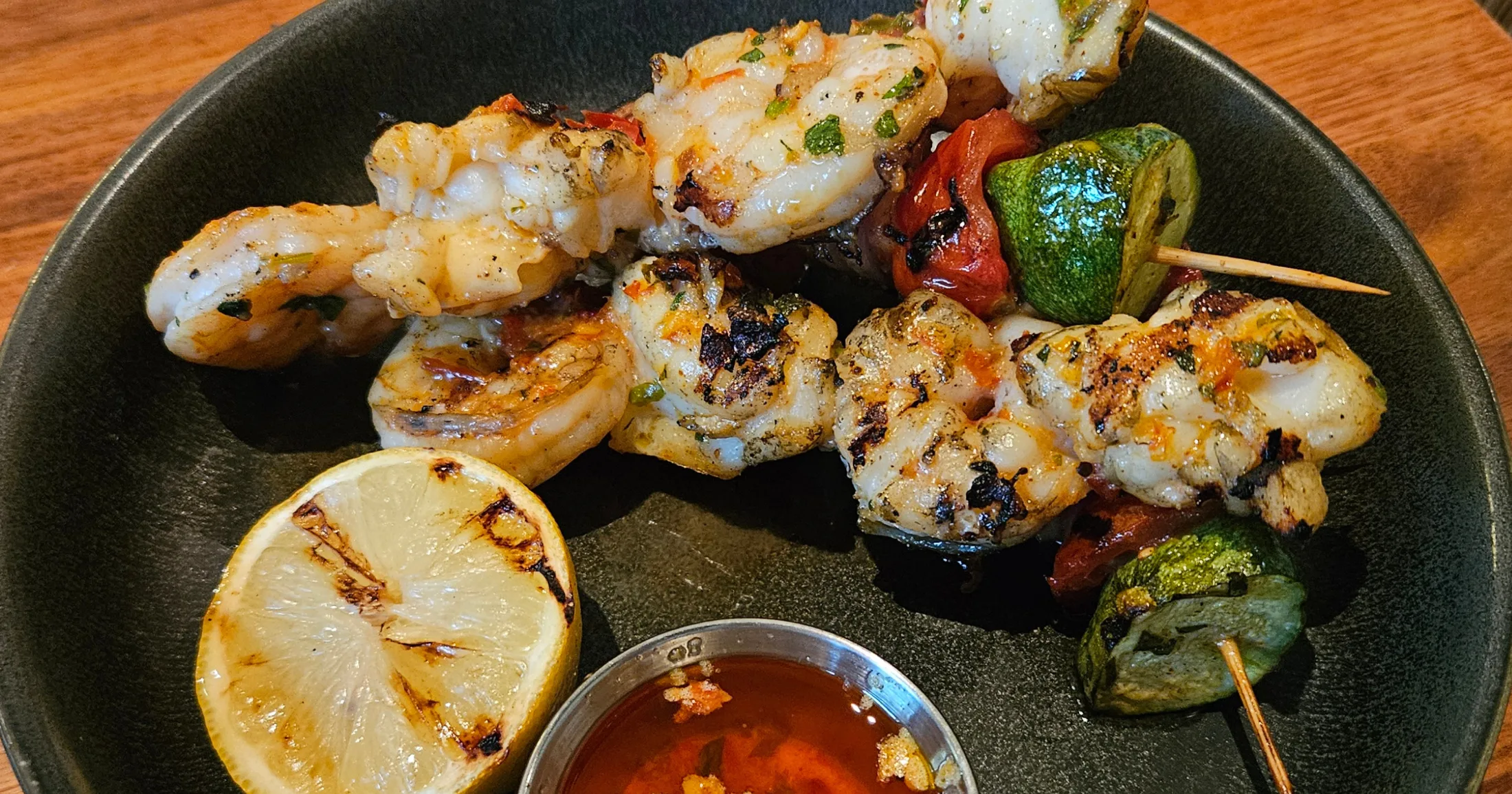 Grilled shrimp and lobster skewers with charred lemon and sweet chili dipping sauce at Tommy Bahama