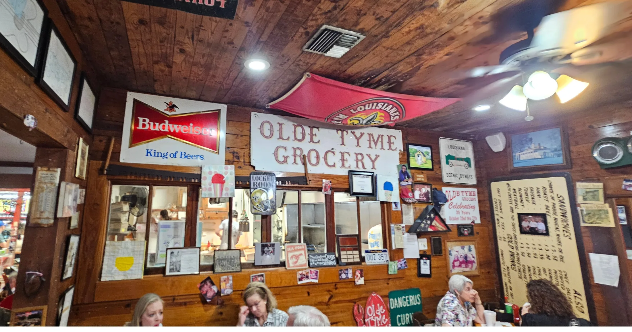 Man eating at an outdoor table under a red umbrella at Olde Tyme Grocery patio