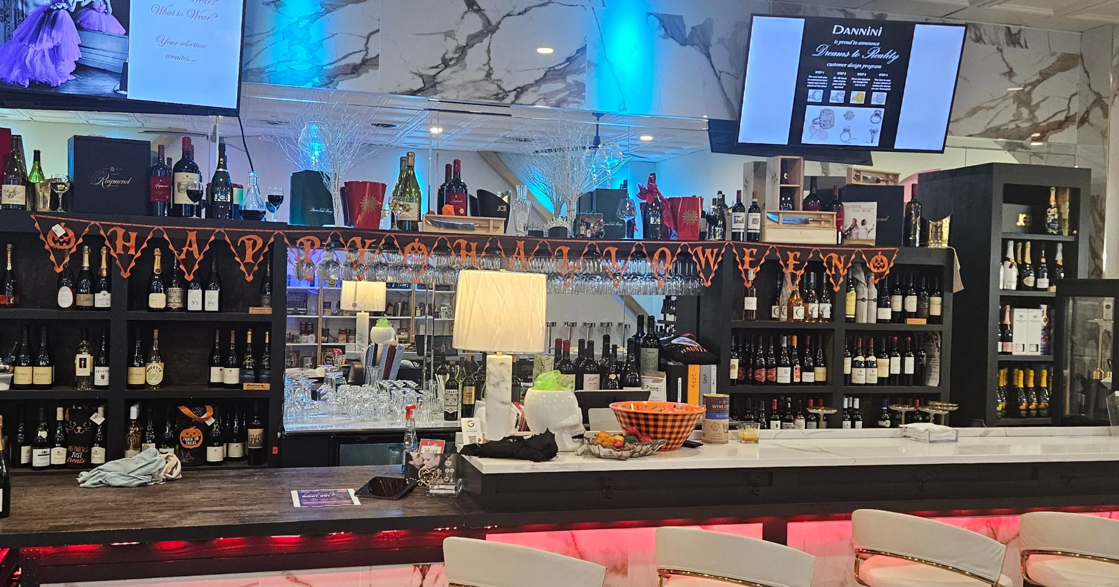 Dannini Luxury Lifestyles bar interior with wine selection, marble surfaces, and Halloween decorations