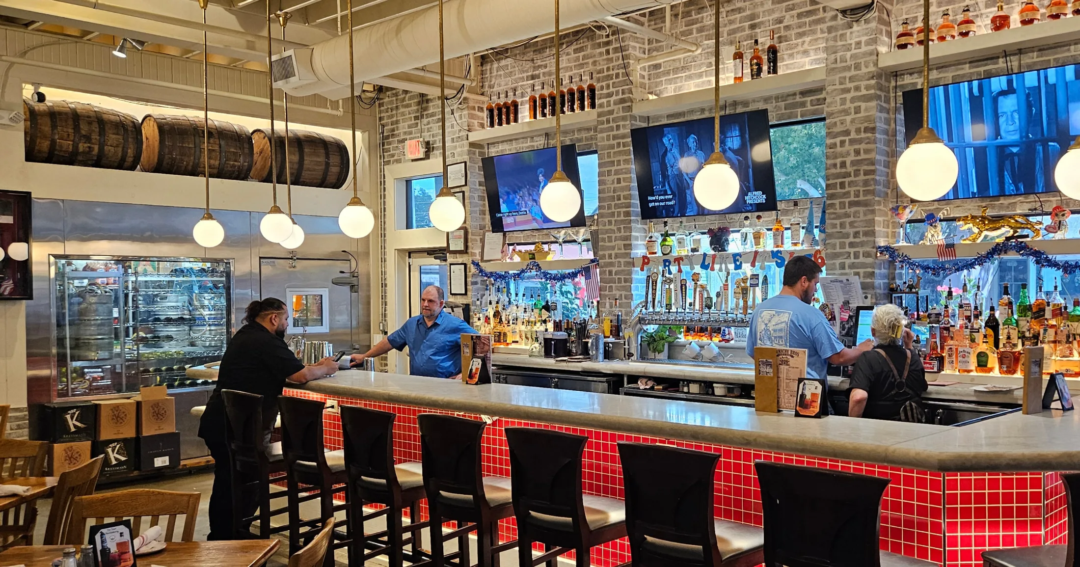 Wunsche Bros. bar with red tile, brass pendant lights, and whiskey bottles on shelves