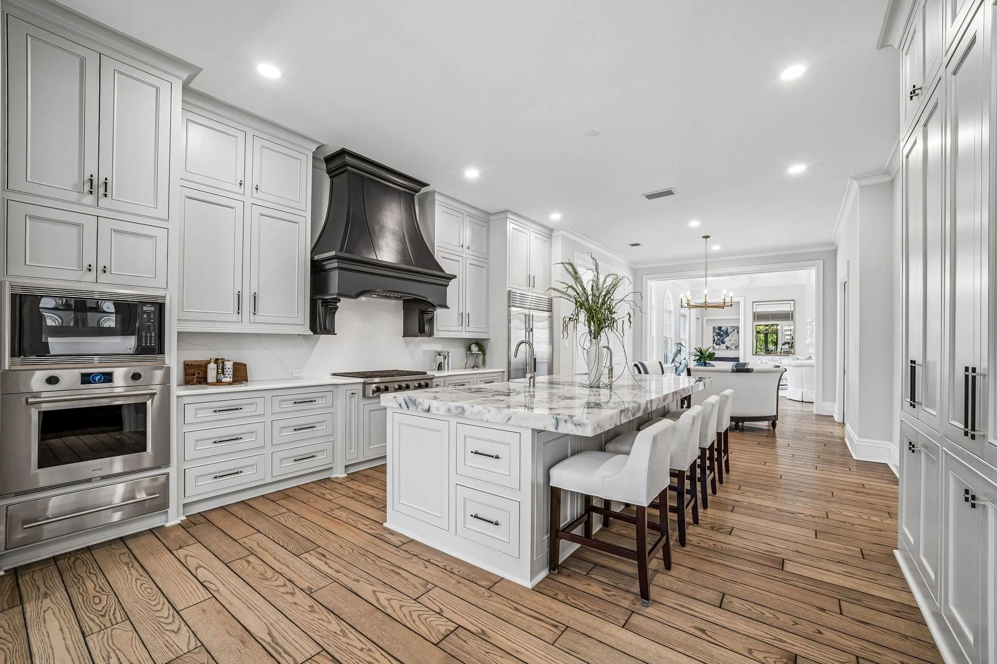 Kitchen at 2 Georgian Row with white cabinetry, marble island, dark range hood, and wide-plank hardwood floors