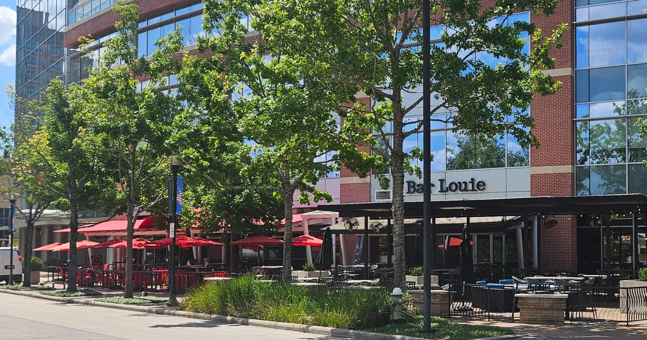 Bar Louie patio with red umbrellas and outdoor seating along the Waterway