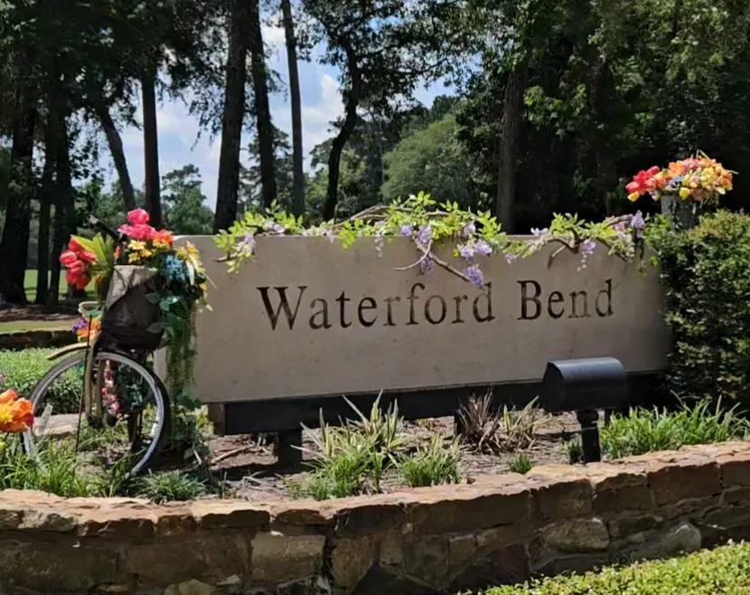 Waterford Bend neighborhood entrance sign decorated with flowers and a bicycle