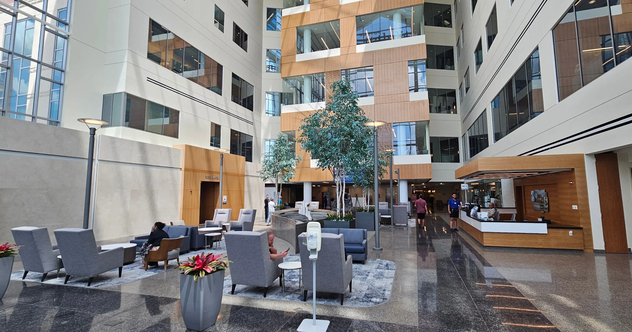 Bright, modern atrium lobby inside a Woodlands hospital with seating areas, live trees, and a reception desk