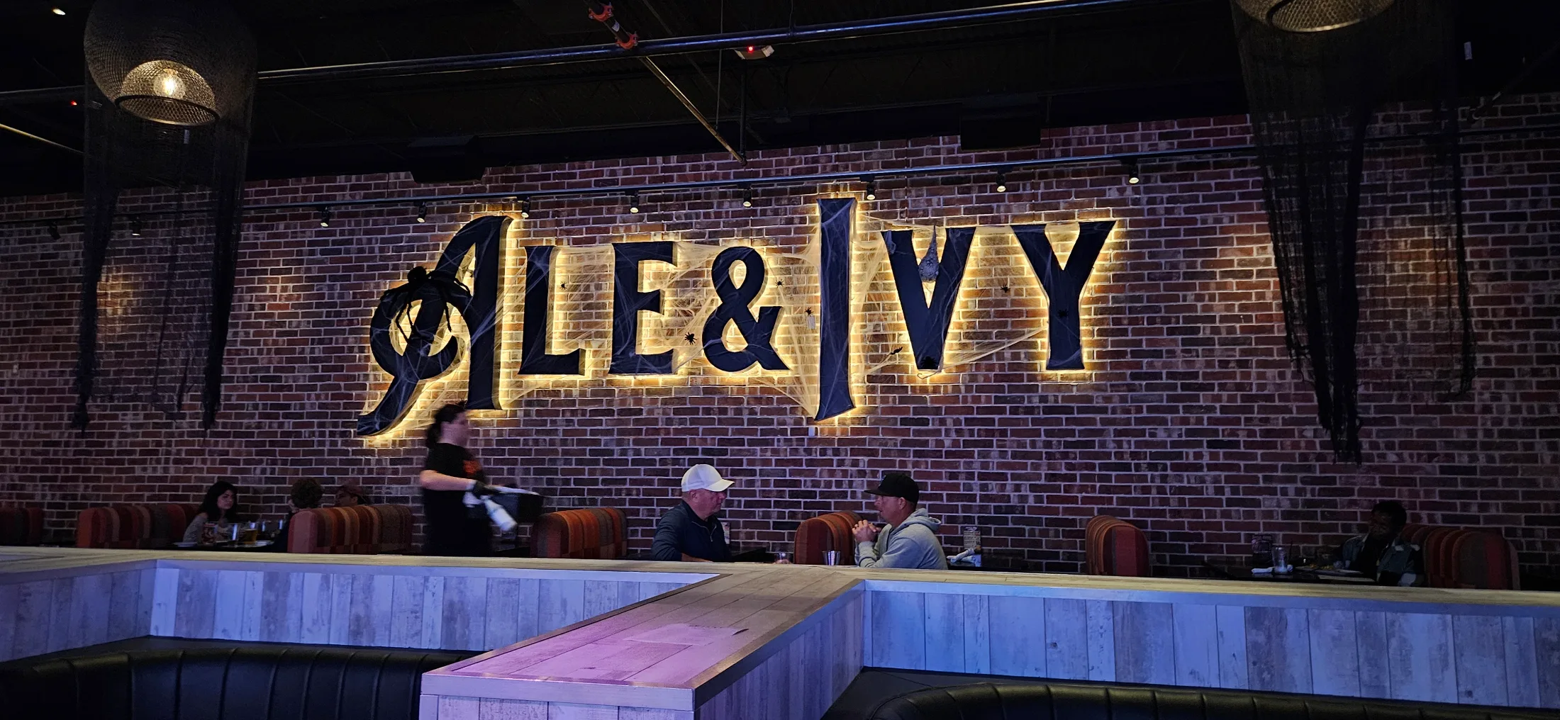 Wide view of the Ale and Ivy main floor showing red pool tables, booths, and multiple sports screens