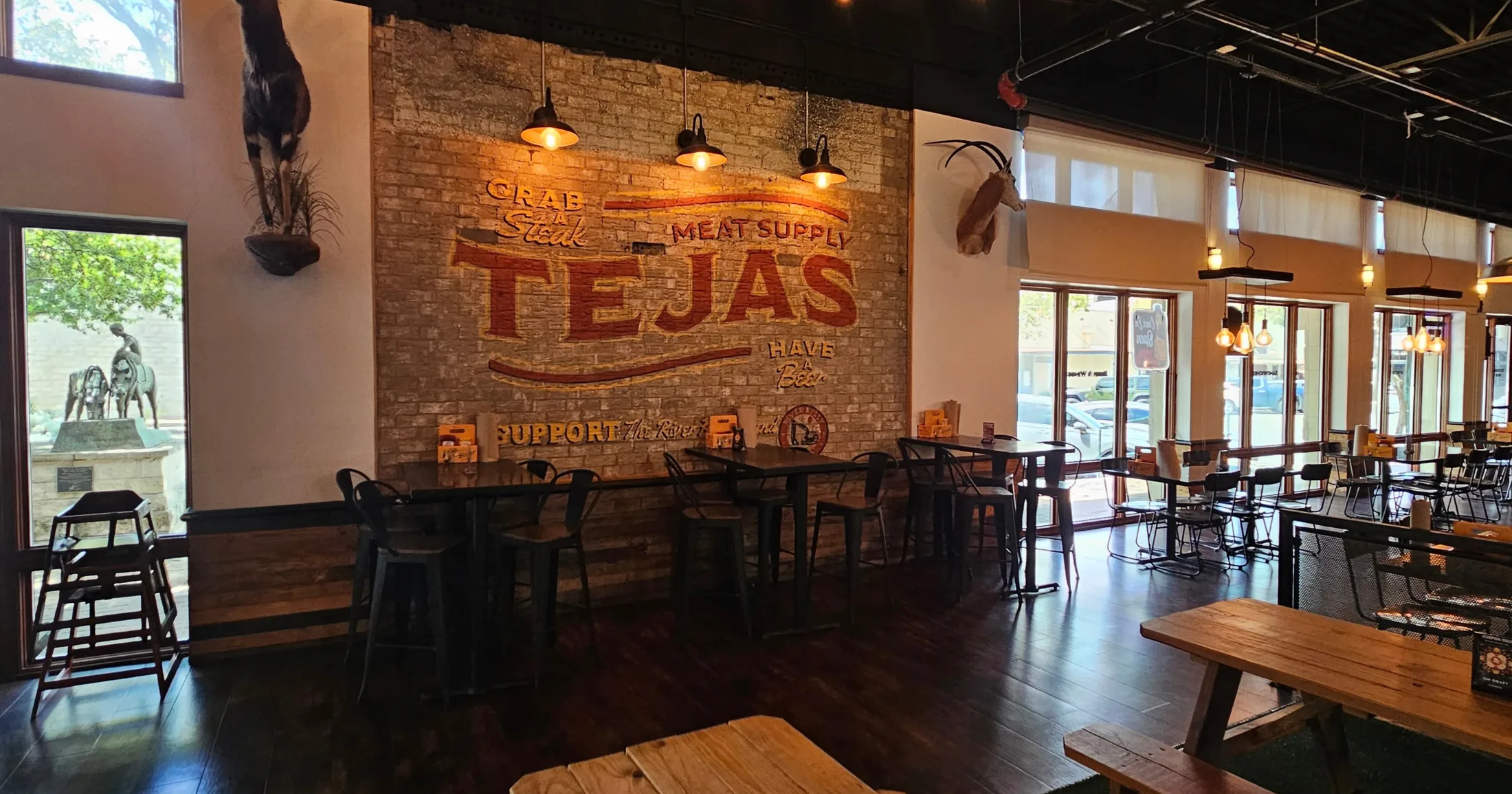 Tejas Meat Supply dining room with exposed brick wall and branded signage in Georgetown, Texas
