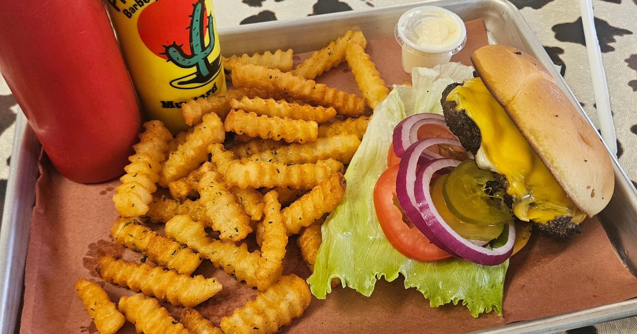 Brisket burger with crinkle-cut fries and house mustard sauce on a metal tray at Pit Master Bar-B-Que