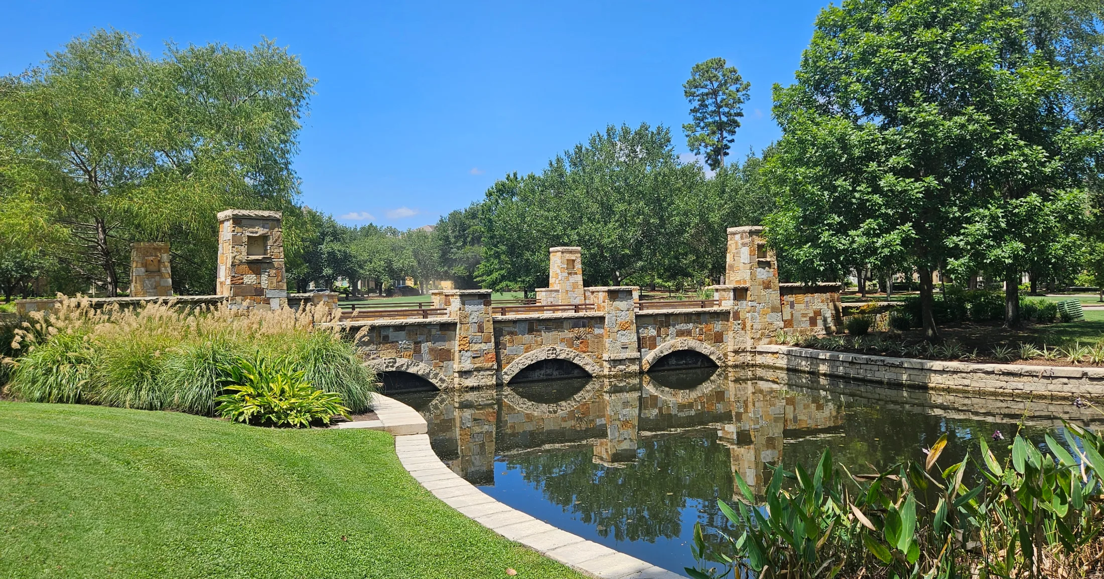 Stone bridge over a reflecting pond in a Woodlands park