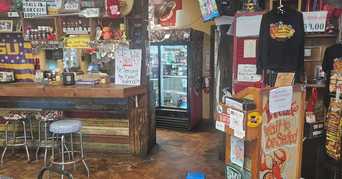 Interior of Crazy 'Bout Crawfish showing the bar, LSU flag, handwritten signs, and Cajun decor