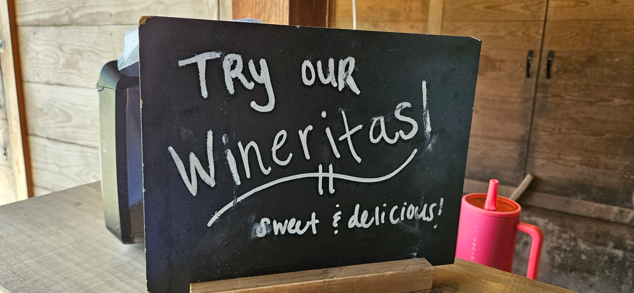Chalkboard sign inside DeepRoots Vineyards reading 'Try our Wineritas — sweet and delicious'