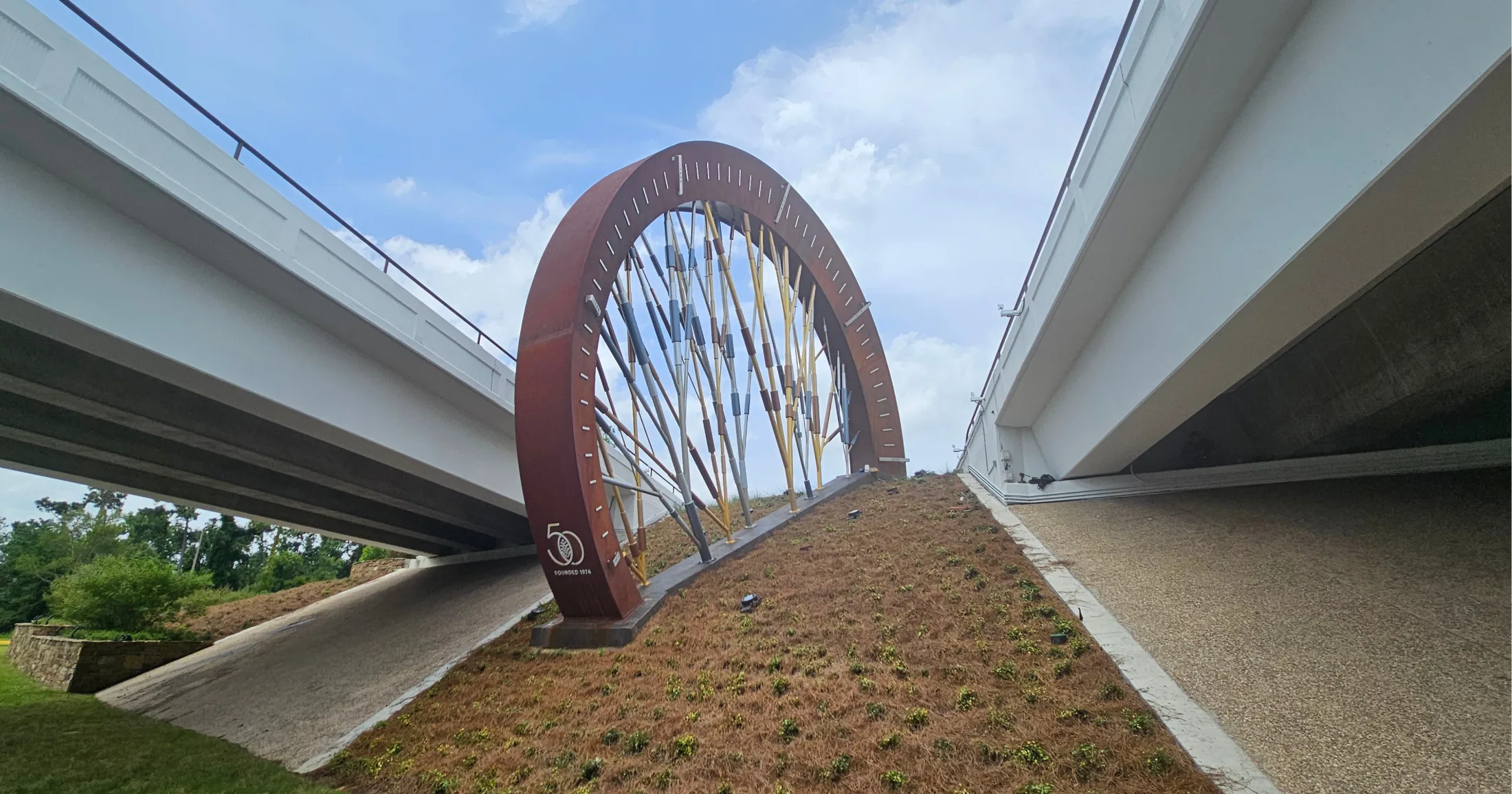 The Woodlands 50th anniversary arch sculpture beneath highway overpass