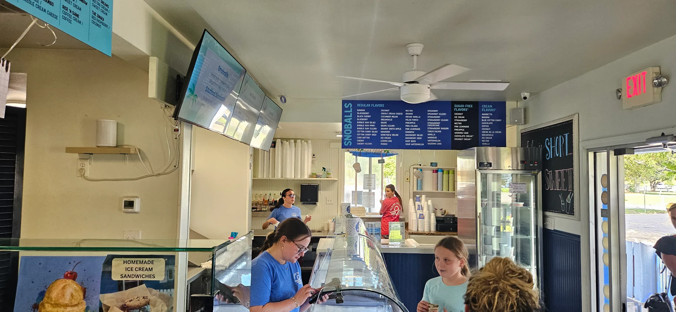 Inside Flying Dolly's showing the counter, homemade ice cream display case, and staff serving customers
