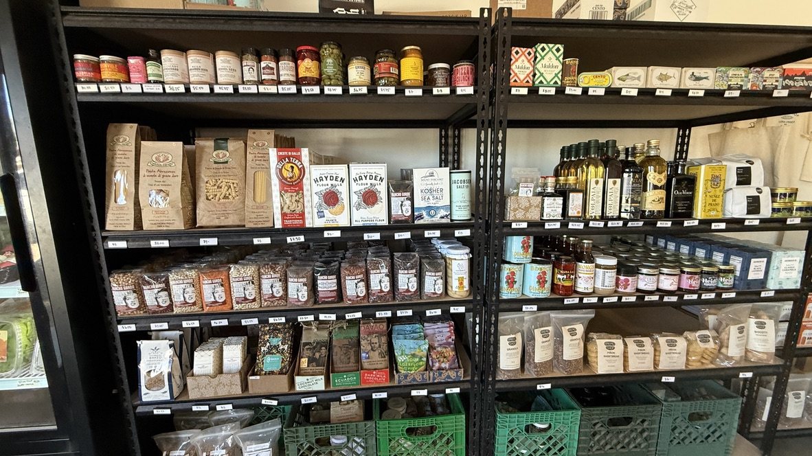 Black metal shelves at Bread Shop stocked with jars, bottles, bags and boxes of pantry goods