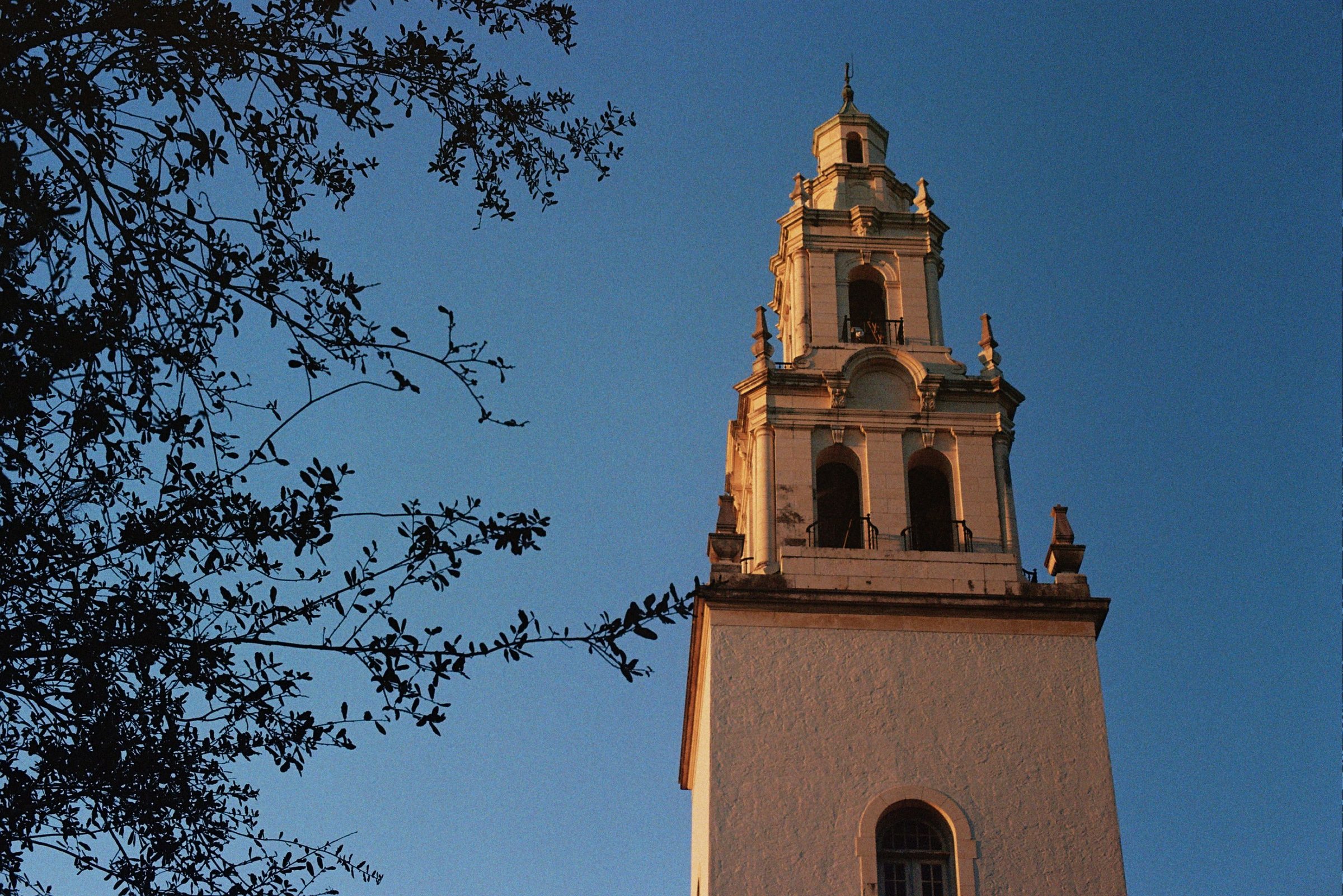 A tall white chapel tower against a clear blue sky