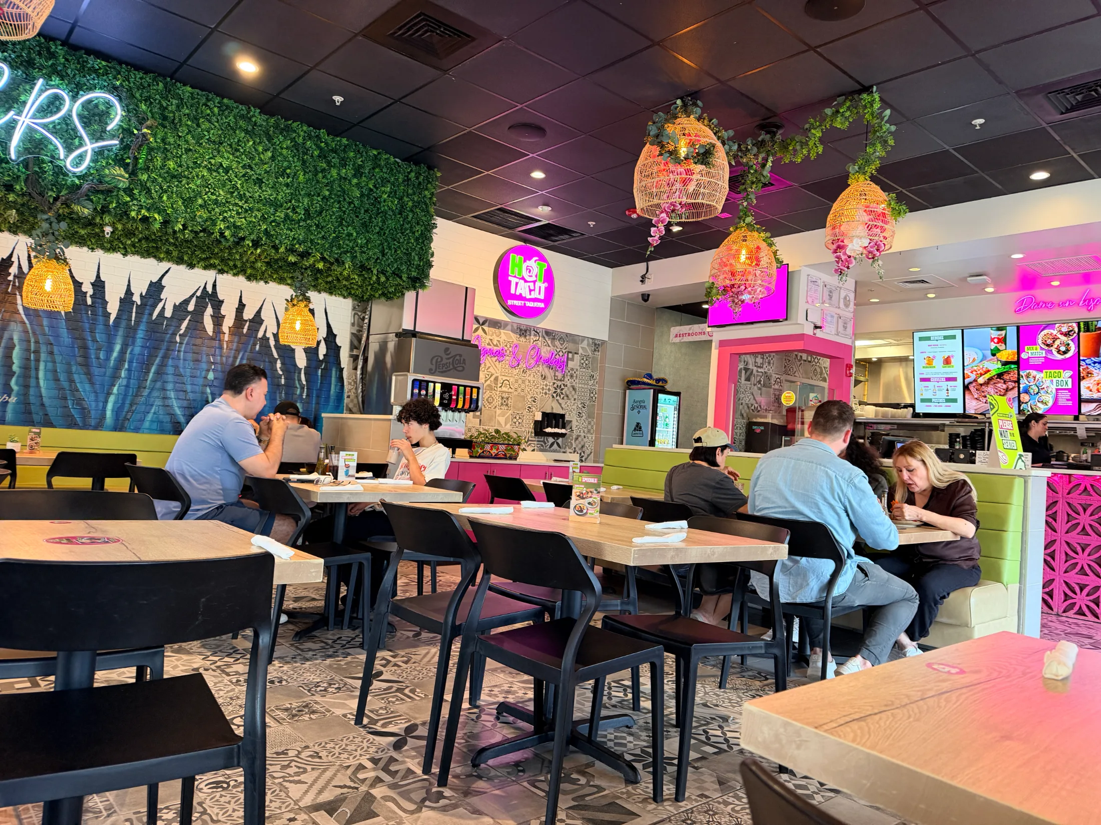 Hot Taco Street Taqueria dining room showing the green wall mural, rattan pendant lights, and colorful interior