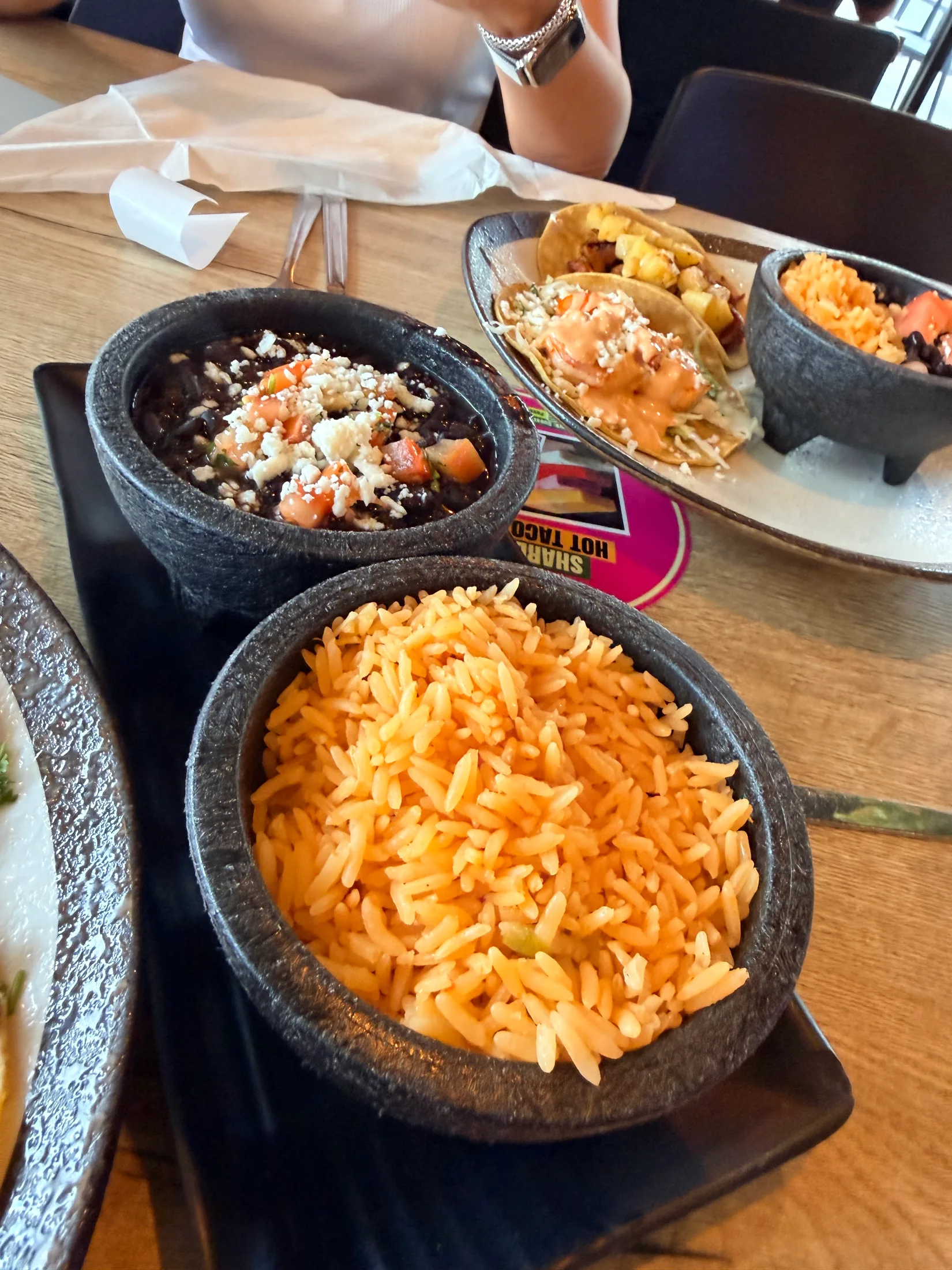 Stone molcajete bowls of Mexican rice and black beans with cotija and tomato at Hot Taco Street Taqueria
