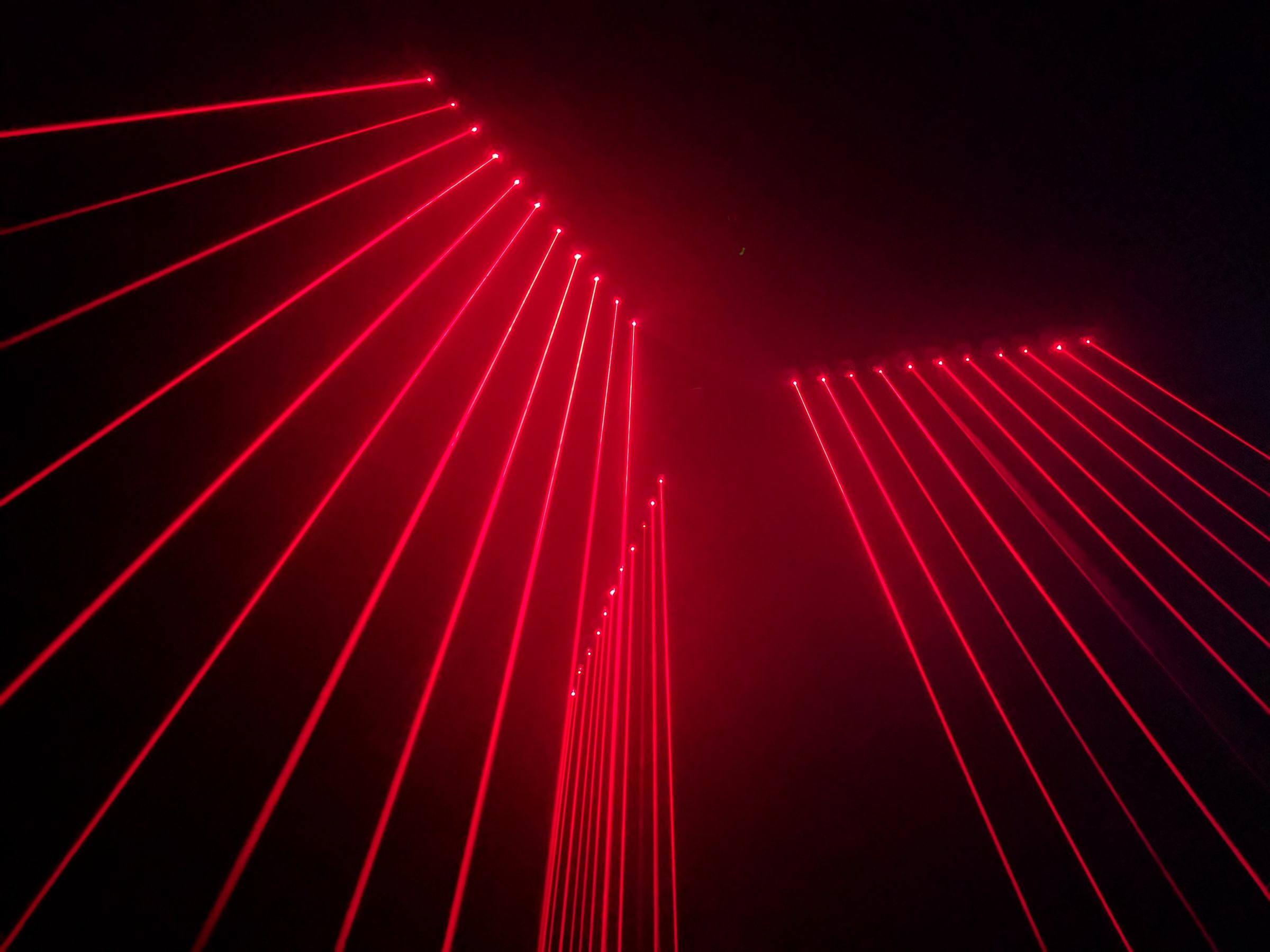 Red laser beams fanning out across a dark room