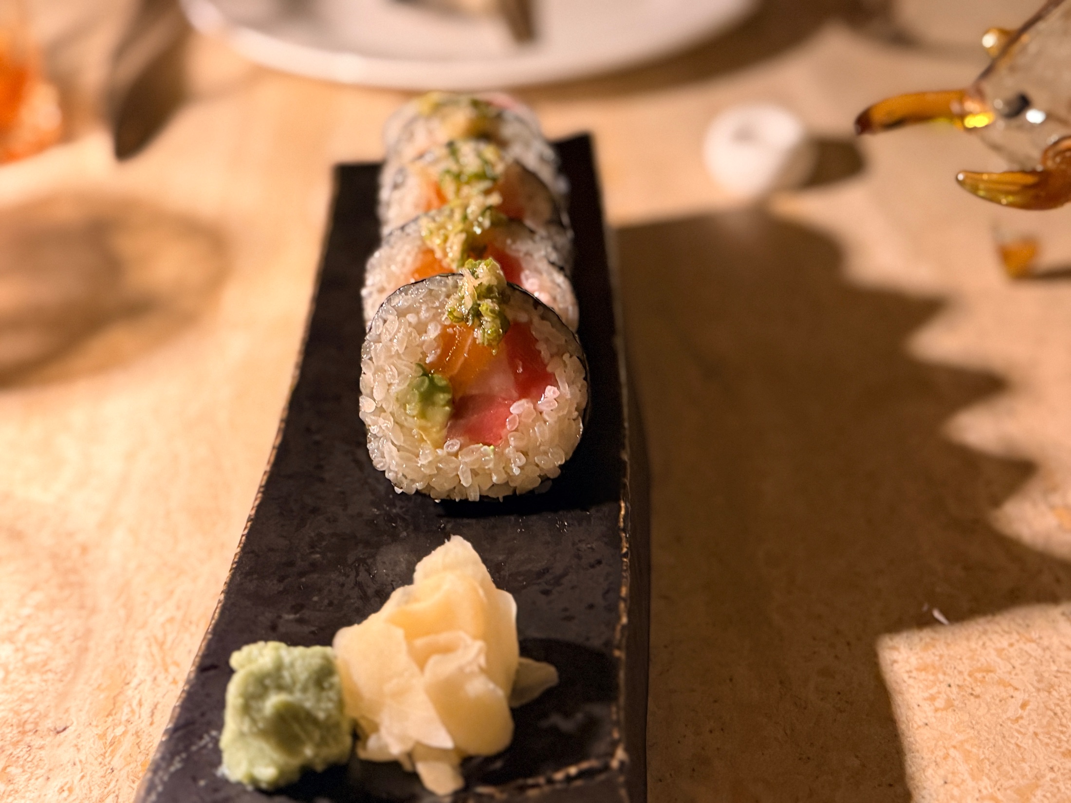 A sushi roll on a dark slate plate with wasabi and pickled ginger at Salt and the Cellar