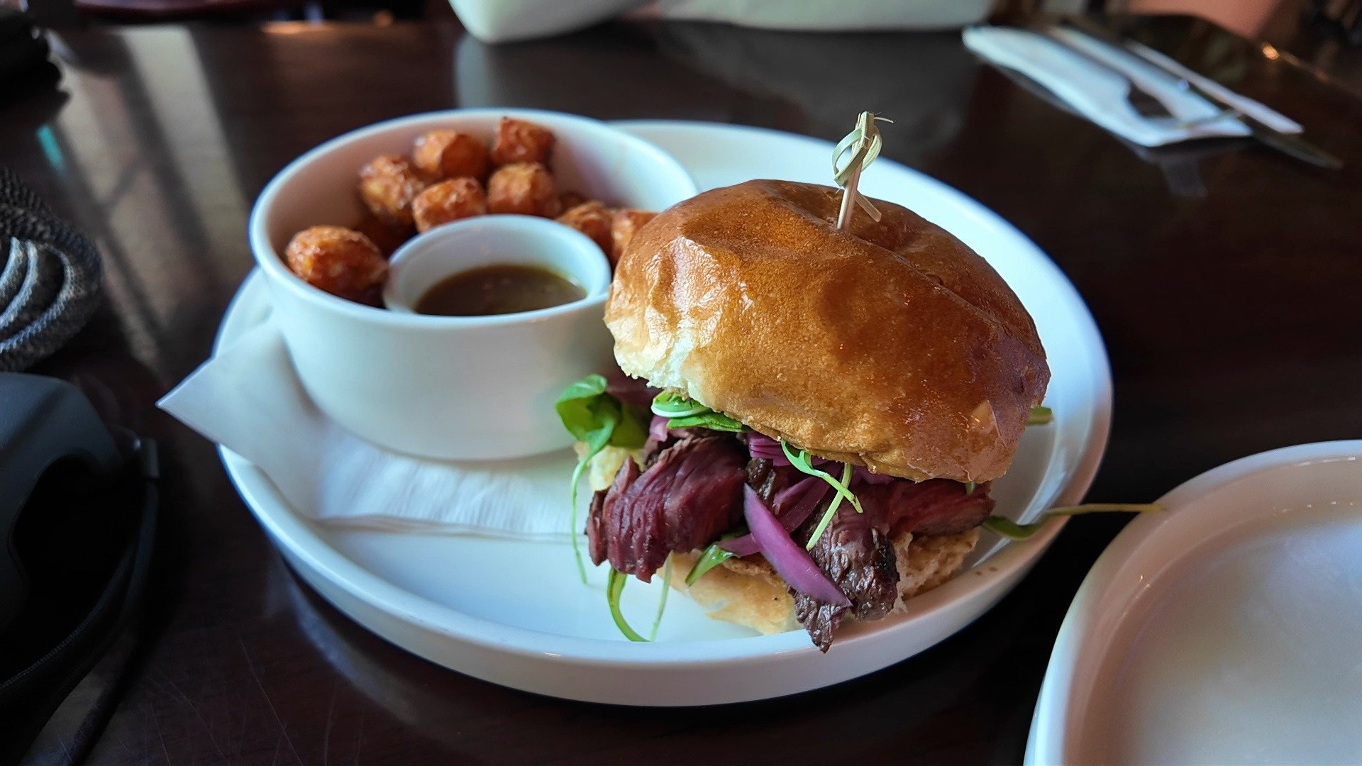 The Hanger sandwich at 2 Floyd's: sliced steak, red onion and greens on a brioche bun, with tots and a dipping cup.